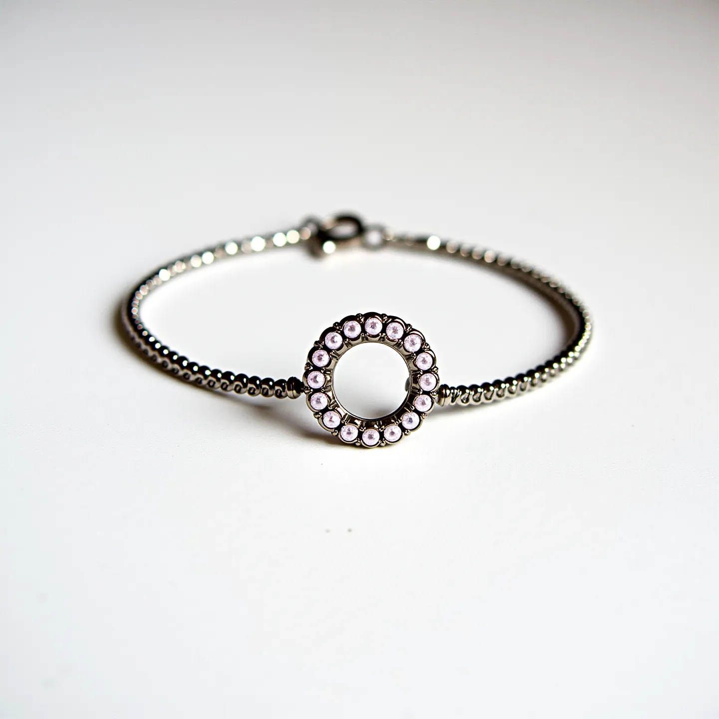 This ankle bracelet features a delicate chain composed of small, uniform metallic beads, likely made from a silver-tone metal. Central to its design is a circular pendant set with a series of small, round, light pink gemstones, which could be either semi-precious stones or high-quality crystals, arranged in a pavé setting around the entire circumference of the circle. The bracelet is secured with a lobster clasp, providing both security and ease of use. The overall design combines elegance with a touch of sparkle, making it a versatile accessory for various occasions.