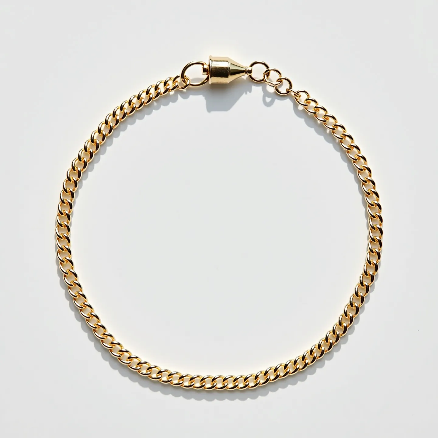 This ankle bracelet appears to be made of a gold-colored metal, formed into a simple yet elegant chain with uniformly interlinked loops, showcasing a classic curb chain design. The bracelet features a cylindrical magnetic clasp, which provides a secure and easy method of fastening and unfastening the piece. Absent of any gemstones, the uniformity of the chain's links lends it a sleek and consistent appearance, contributing to the overall aesthetic appeal and wearability of the accessory.