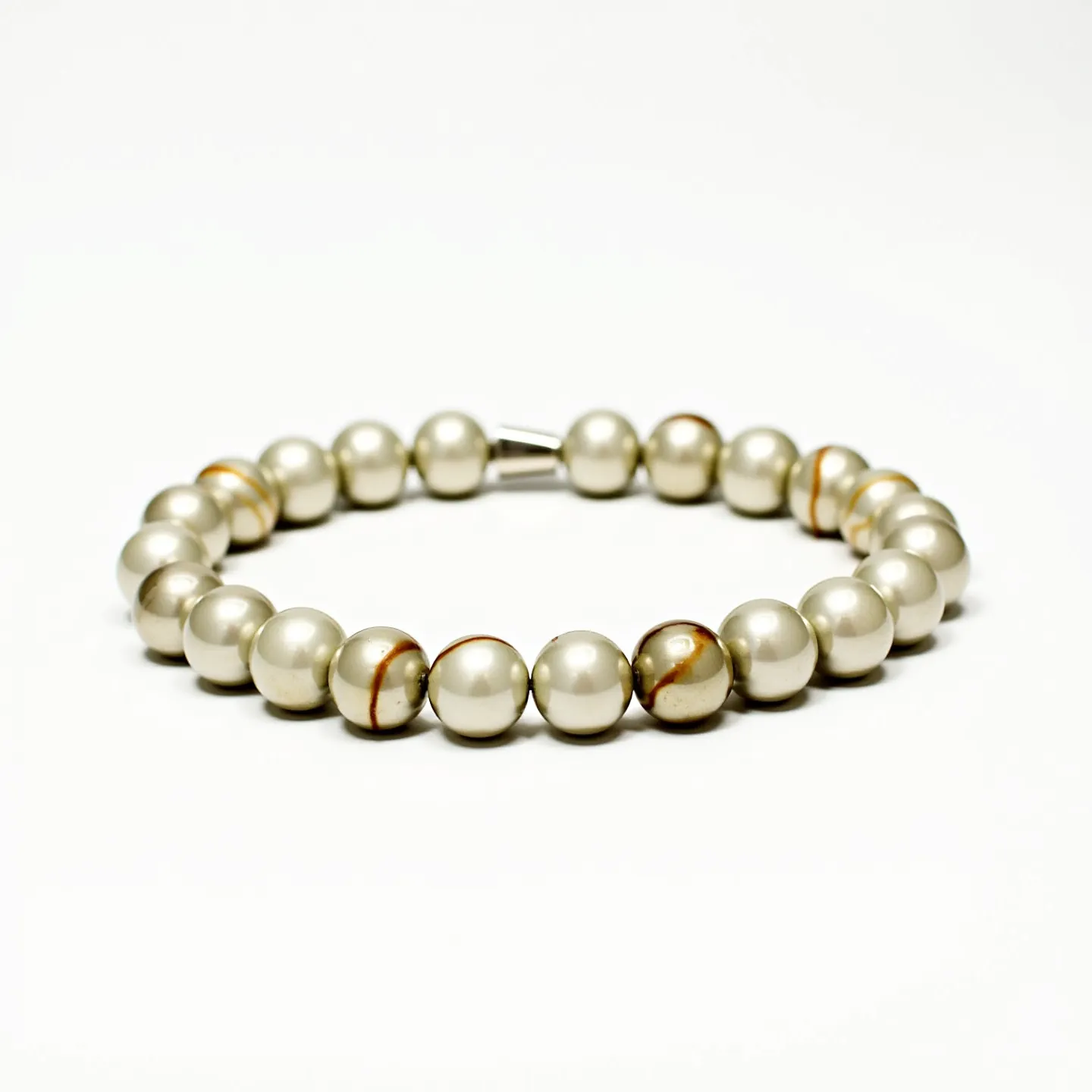 This baby bracelet features a series of round, evenly-sized beads that appear to be made from a smooth, shiny material resembling pearls or high-quality faux pearls. The beads are predominantly a soft silver or light gray color, with a few beads displaying a natural-looking brown and cream pattern, suggesting possible variations in the material used. The bracelet is likely strung on an elastic cord, which allows it to stretch, making it easier to put on and take off without the need for a traditional clasp or attachment mechanism. The overall design is simple yet elegant, suitable for a baby.