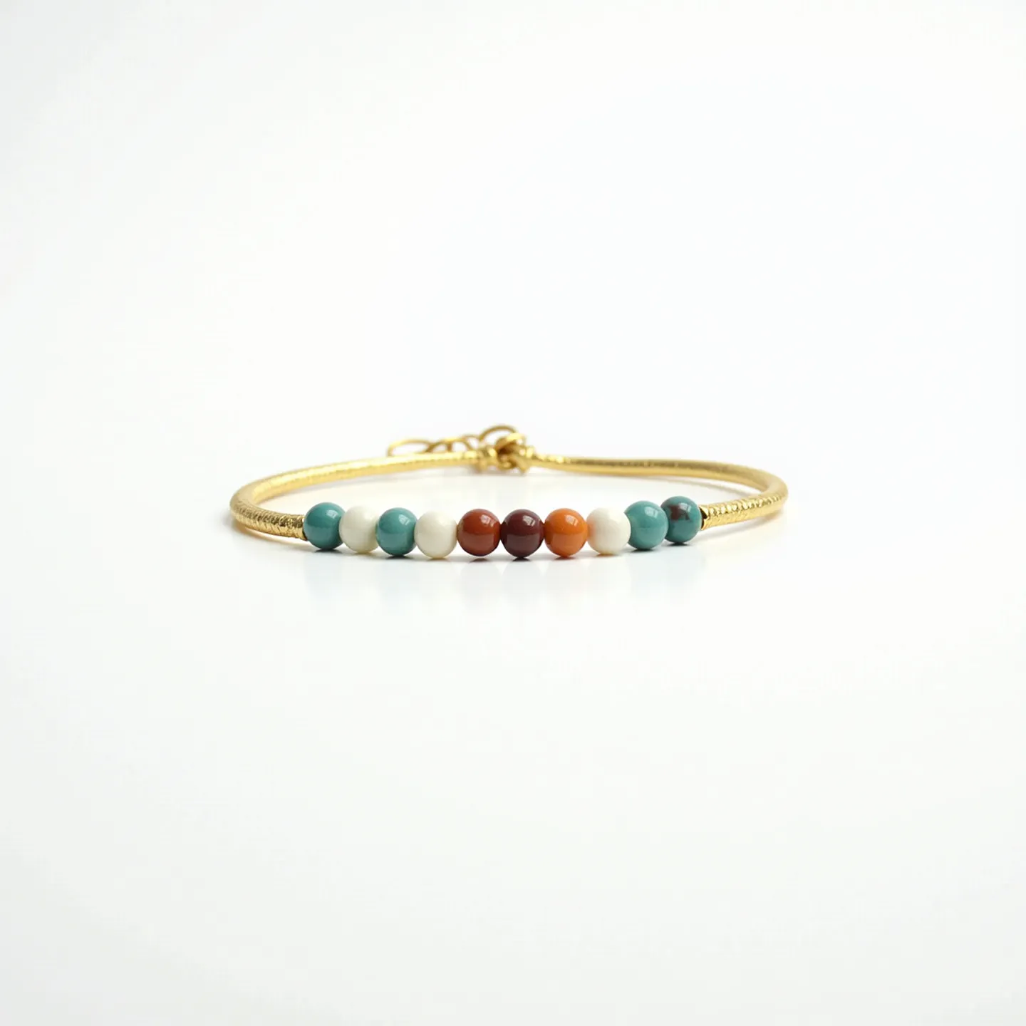 This baby bracelet features a delicate gold-colored band adorned with small, round beads. The beads are multi-colored, including shades of turquoise, white, orange, and brown, creating an attractive and colorful pattern. Each bead is smooth and polished. The bracelet is secured with a simple hook clasp, ensuring that it stays securely on a baby's wrist while being easy to put on and take off.