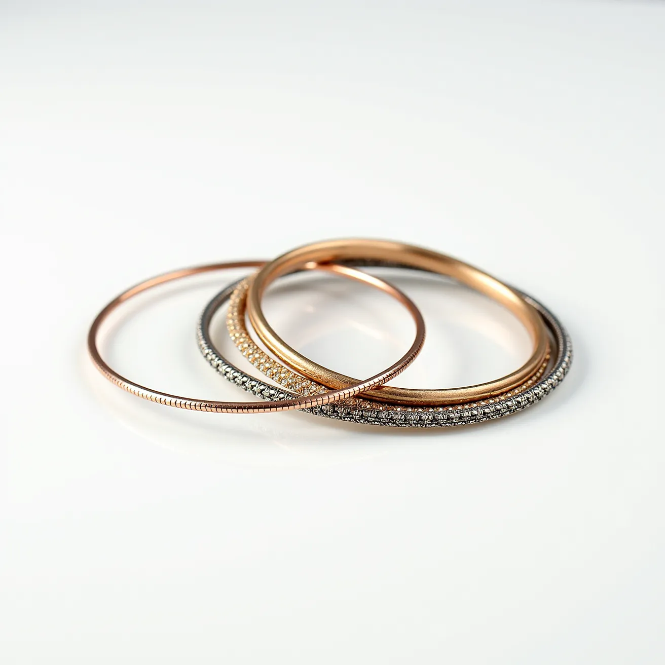 This bangles are an elegant ensemble featuring multiple pieces made from metal materials, likely consisting of gold and silver tones. They include one bangle adorned with a continuous row of small, round-cut gemstones, likely diamonds, set in a pavé setting to ensure each stone is securely fastened and showcases a seamless, glittering effect. Another bangle, smooth and simple, exhibits a high-polish finish, highlighting the metal's natural sheen, while a third narrow bangle displays subtle textural details, likely achieved through etching or precision milling, providing a sophisticated yet uniform appearance. These bangles are designed to be slipped over the wrist without the need for a clasp or additional attachment mechanism, emphasizing their sleek and unbroken circular form.