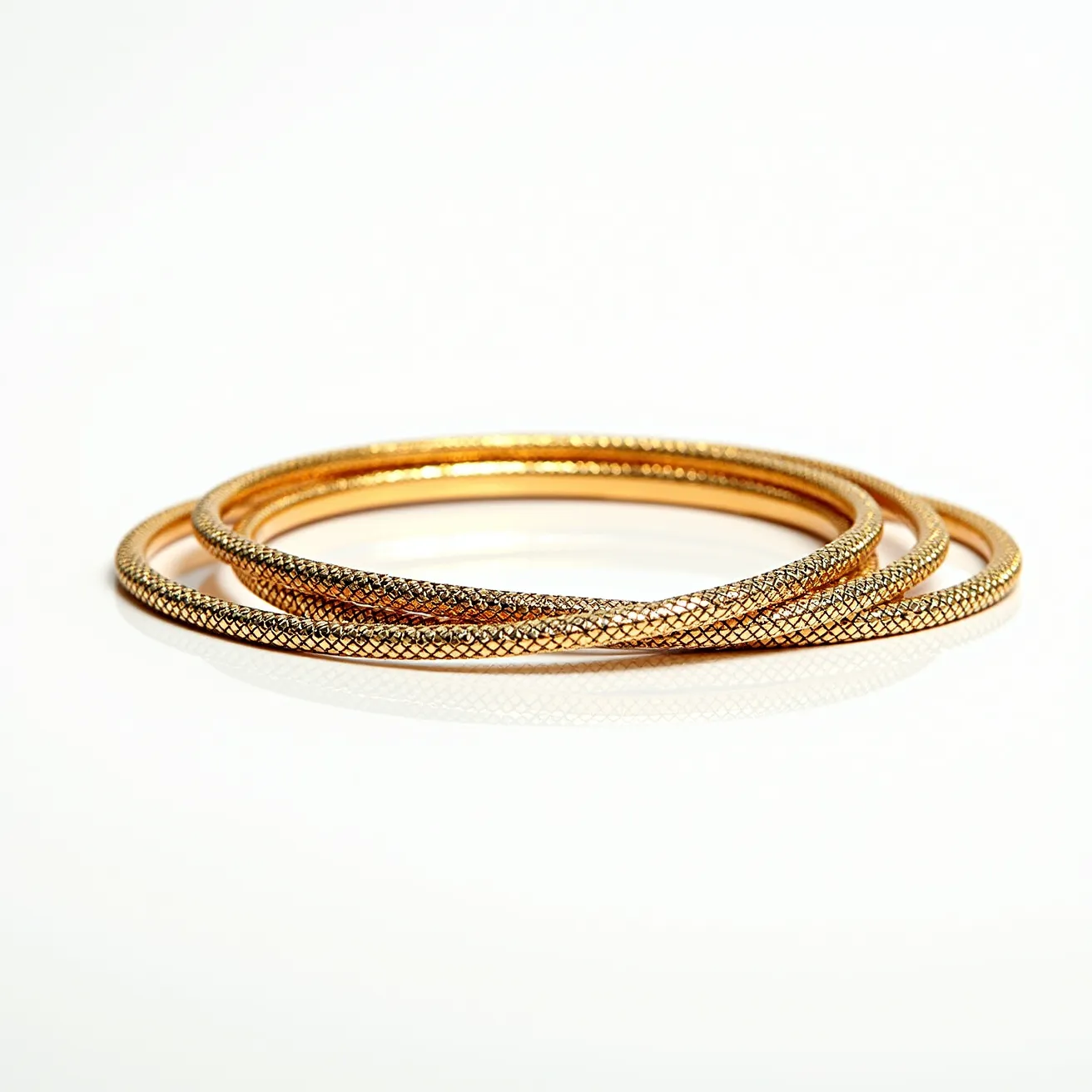 This bangles are crafted from a metallic material, likely gold or gold-plated, featuring an intricate pattern that creates a textured surface. The design includes a crosshatch or grid-like motif, providing a sophisticated and stylish appearance. There are no visible gems or stones on the bangles, and the design appears uniform across the entire circumference. The bangles do not feature any clasps or attachments, indicating they are likely slip-on style, designed to fit over the hand. The overall aesthetic is elegant and timeless, suitable for both casual and formal wear.