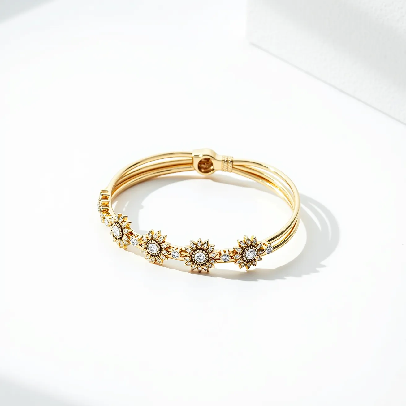 This bangles features a gold-toned metallic base crafted into a triple-band design. Adorning the bangle are multiple sunflower-shaped elements, each embellished with a central round-cut gemstone that appears to be a clear, sparkling stone, possibly a diamond or a high-quality crystal. The sunflower petals surrounding the central stone add an intricate and elegant detail, giving the bangle a unique and stylish appearance. The bangle is secured with a clasp that integrates seamlessly with the design, ensuring both functionality and aesthetic cohesion.