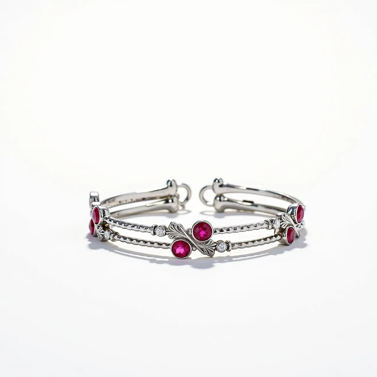 This bangles features a delicate design crafted from a silver-toned metal, adorned with vibrant, round-cut red gemstones that are bezel-set along its length. The red gemstones are complemented by smaller clear stones, which are also bezel-set, adding to the bangles' elegance and sparkle. The bangle appears to have a unique dual-band structure, with intricate detailing where the stones are set. It includes a secure clasp mechanism at the end, ensuring it stays firmly in place when worn. The combination of the red and clear stones with the silver-toned metal creates a striking, elegant appearance.