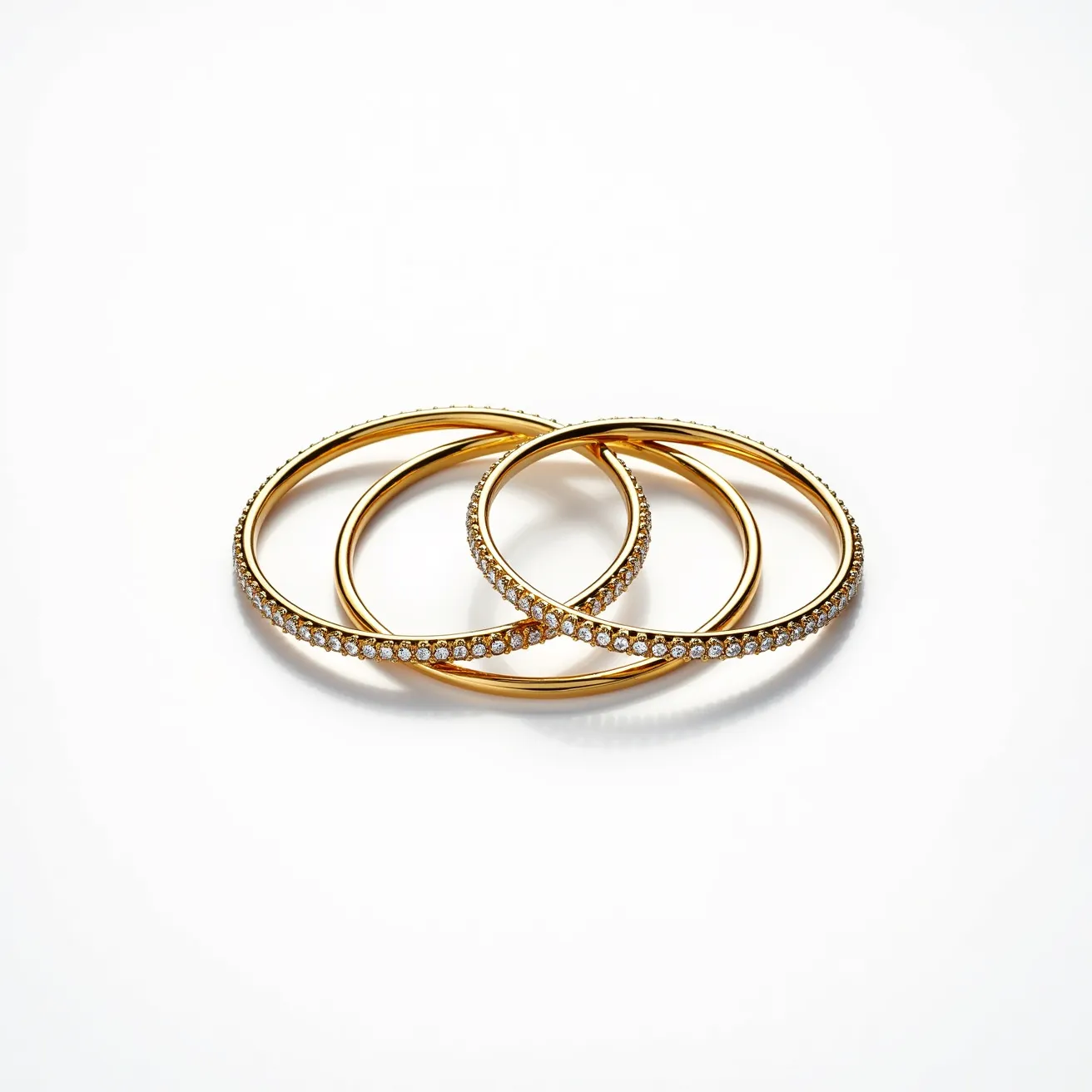 This bangles are crafted from a golden-hued metal, showcasing a classic and elegant design. Each bangle is adorned with small, round-cut gems, likely diamonds or cubic zirconias, that are uniformly set in a single row around the entire circumference of the bracelet. The gems are prong-set, ensuring they are securely fastened, and their arrangement adds a continuous sparkle to the bangles. The bangles do not feature any clasps or hinges, indicating that they are designed to be slipped onto the wrist. They exhibit a smooth, polished finish, enhancing their sophisticated appearance and making them a timeless addition to any jewelry collection.