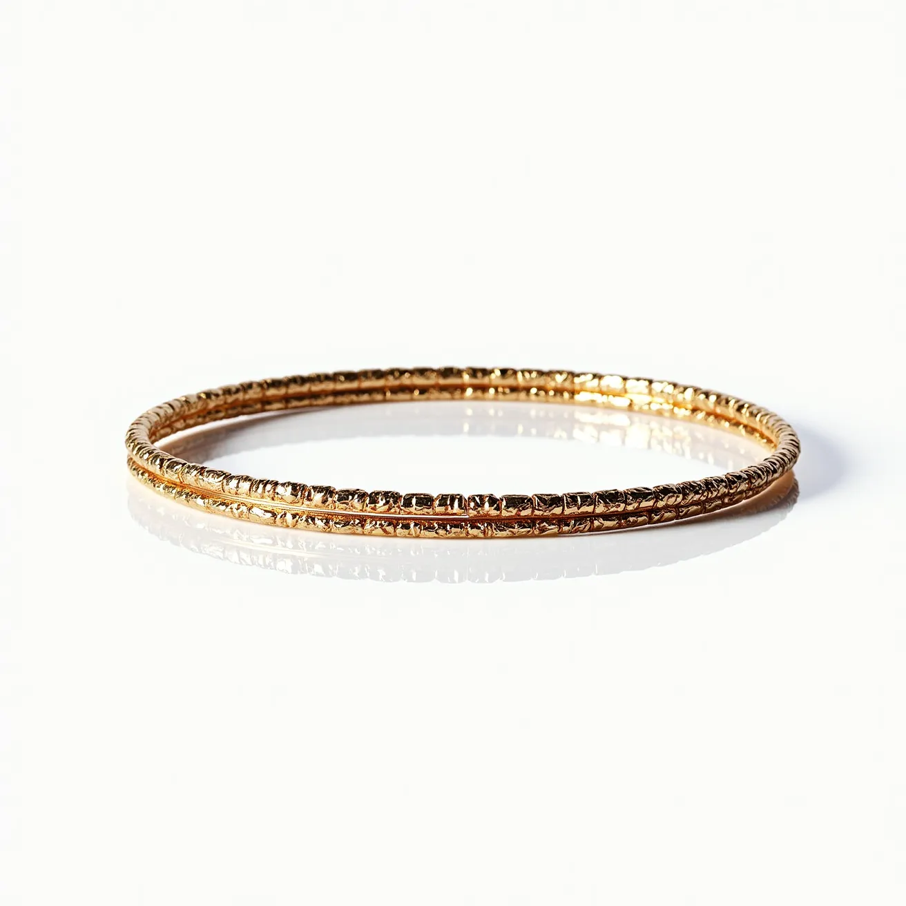 This bangles feature a delicate, intricate design crafted from a material with a gold-like appearance, suggesting it may be gold or gold-plated metal. The surface is textured with fine detailing, giving the bangle a rich and ornate look. There are no visible gems, stones, or additional settings embedded in the bangle. The bangles appear to be of slip-on style with no visible clasps or attachments, making them a continuous circular band.