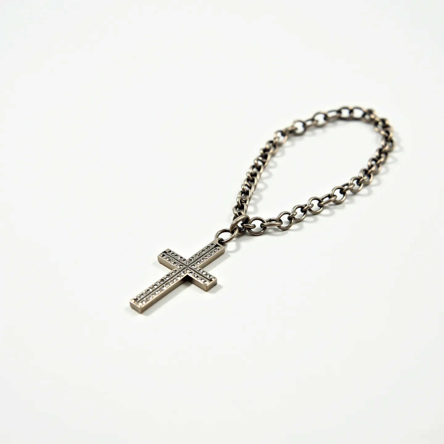 This cross bracelet features a silver-colored chain link strap and a prominent metal cross pendant. The cross is designed with detailed engravings that add texture to its surface, appearing to be studded with small gems that reflect light subtly. The bracelet includes a secure clasp mechanism, ensuring it remains firmly attached when worn. The minimalist yet elegant design makes it a versatile accessory suitable for various occasions.