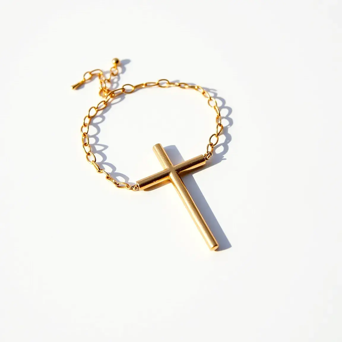 This cross bracelet features a polished, metallic cross pendant held by a chain composed of interlocking gold-colored links. The cross appears to be made of a metal with a smooth, reflective finish. The bracelet is secured with a lobster clasp, which is attached to an adjustable chain that allows for modifications to the bracelet's length. The minimalist design of the cross pendant is complemented by the simple and elegant chain, creating a stylish and timeless accessory.