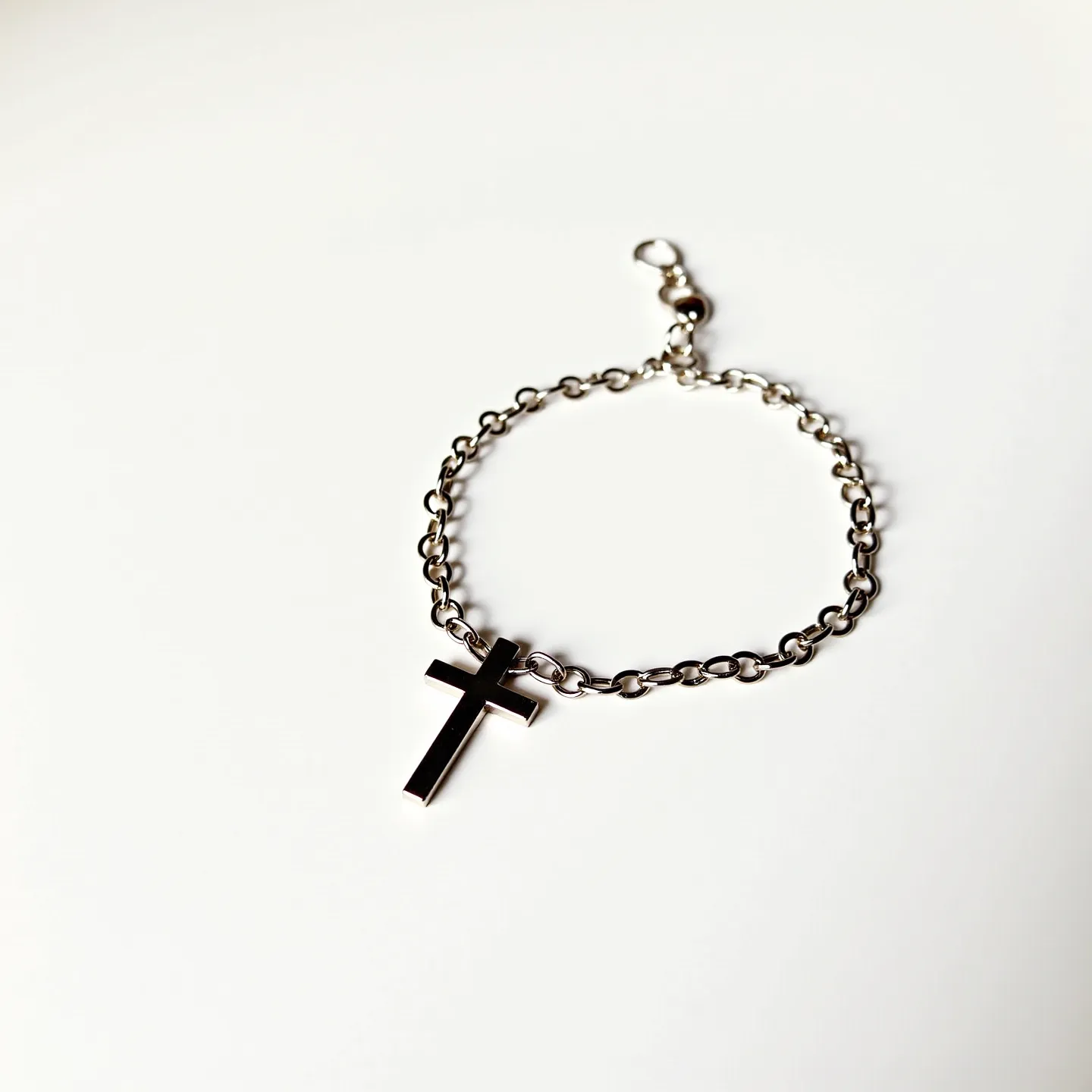 This cross bracelet features a durable chain made of metal links, each one carefully interlocking with the next to form a cohesive unit. The centerpiece of the bracelet is a sleek cross charm, also crafted from the same metallic material, showcasing a polished finish that catches the light and adds a touch of elegance. The bracelet is secured with a simple yet effective lobster clasp, ensuring that it remains securely fastened while being easy to put on and take off. This piece exudes a minimalist design, focusing on the clean lines and reflective quality of the metal.