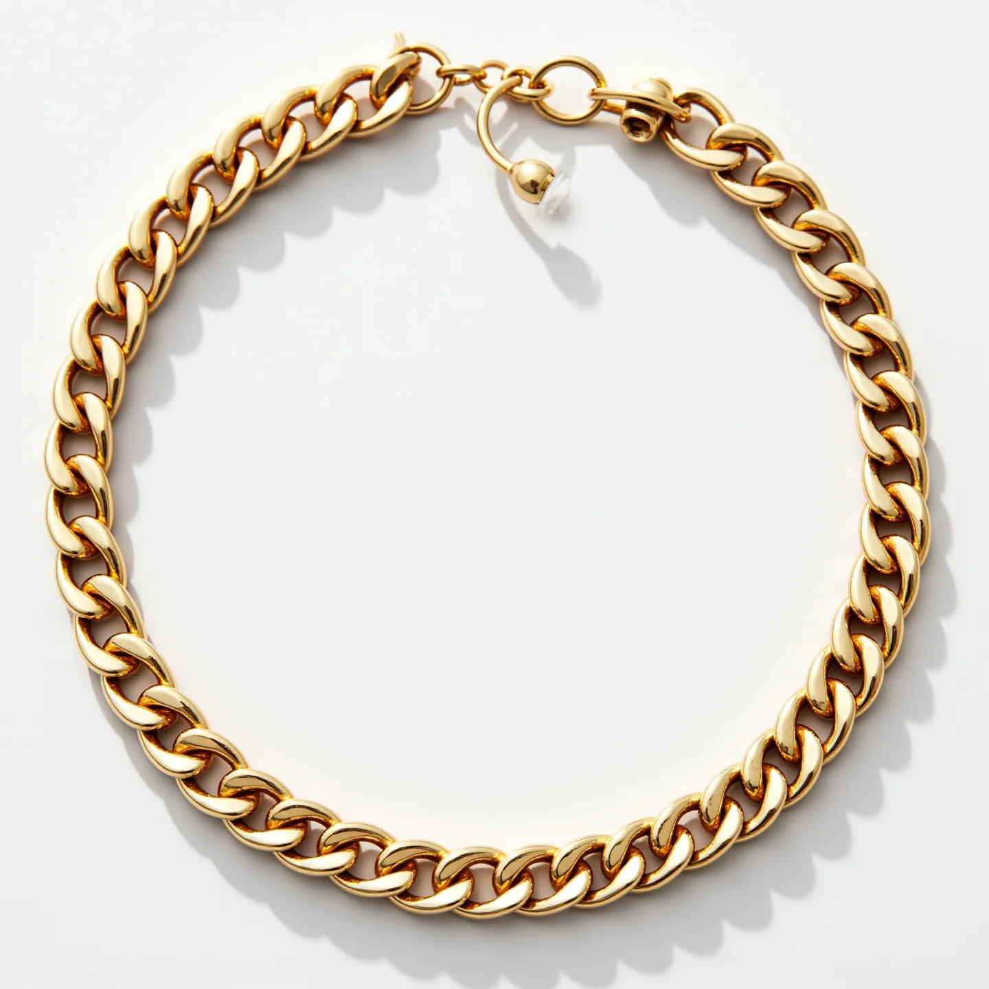 This cuban link bracelet features tightly interlocking links made from a polished gold metal, giving it a smooth and shiny appearance. It is devoid of any gemstones, focusing entirely on the lustrous metalwork. The clasp is designed as a circular push-lock mechanism, ensuring secure and easy fastening and removal. The overall design exudes a classic, elegant style, suitable for both casual and formal wear.