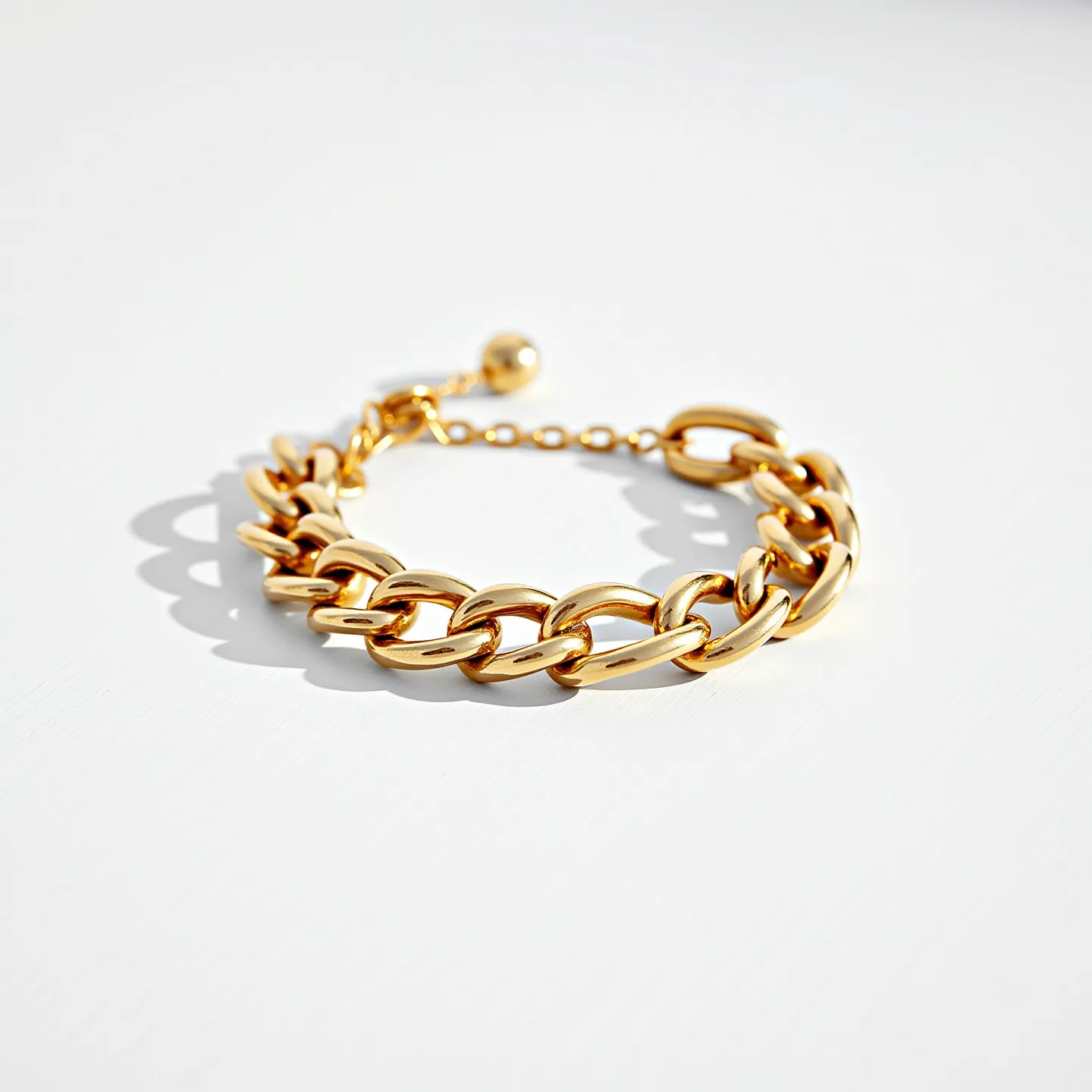 This cuban link bracelet showcases a classic and elegant design with its polished gold material, giving it a luxurious appearance. The links are uniformly crafted in the characteristic interlocking pattern that defines the cuban link style. The bracelet features a simple yet secure clasp mechanism, complete with an adjustable chain that ends in a small spherical charm, enhancing both its functionality and aesthetic appeal.