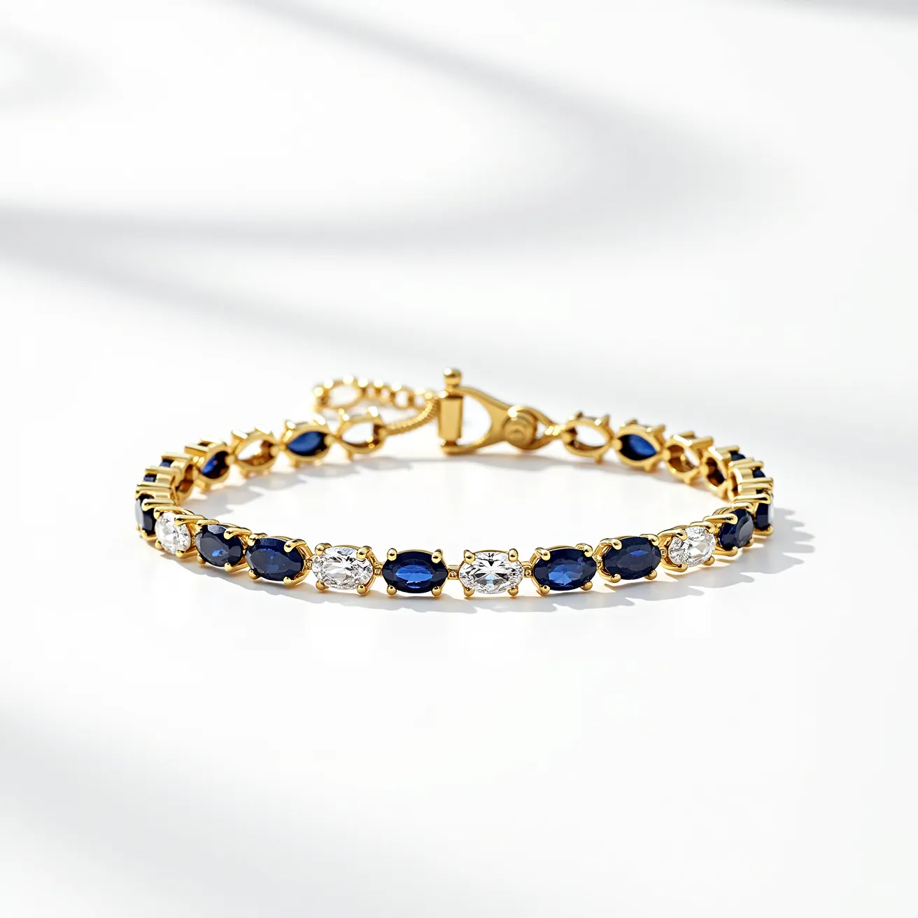 This diamond tennis bracelet features a series of alternating oval-cut blue sapphires and round-cut diamonds, each set in gold prongs. The sapphires exhibit a rich, deep blue hue, complementing the brilliance of the diamonds. The bracelet is crafted from a polished gold material, which adds a luxurious touch to the overall design. It is secured with a gold clasp, ensuring a seamless and elegant appearance when worn.