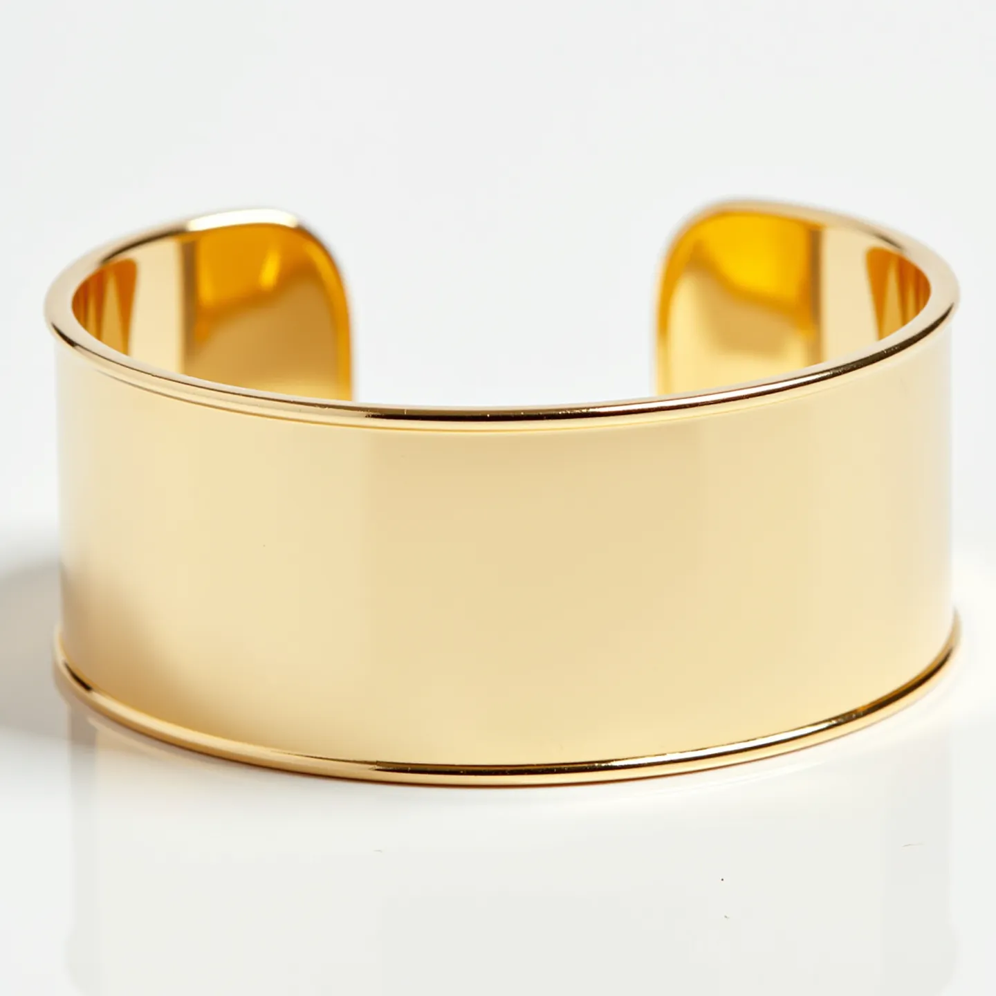 This gold cuff bracelet exhibits a sleek and polished design, crafted from high-quality gold. The bracelet features a smooth, broad surface with a mirror-like finish, adding to its elegant and luxurious appearance. The cuff style ensures an easy and comfortable fit on the wrist, with a slight gap allowing for adjustment. The edges of the bracelet are slightly beveled, providing a refined touch to its overall simplicity and sophistication.