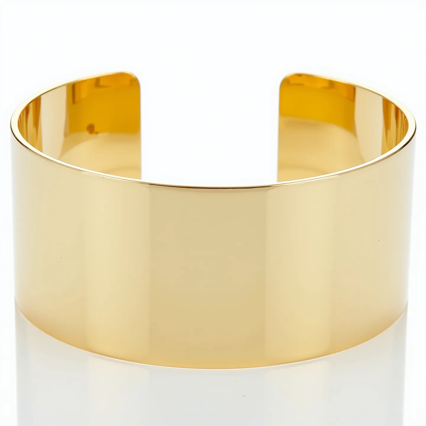 This gold cuff bracelet showcases a sleek and polished surface with minimalistic design elements. It is crafted from high-quality gold, evident from its lustrous sheen. The bracelet is designed with an open-ended cuff style, allowing it to comfortably fit various wrist sizes without the need for a clasp or additional attachment. The smooth, reflective surface highlights the craftsmanship and quality of the material used in its creation. The simplicity of the design along with its high-gloss finish makes it a versatile piece suitable for a variety of occasions.