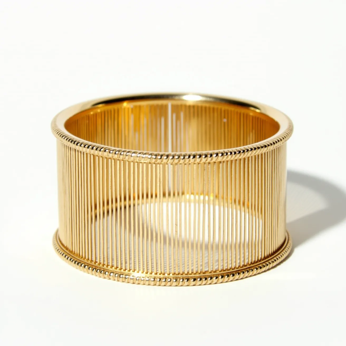 This gold cuff bracelet exhibits an intricately crafted design featuring numerous thin, parallel gold bars that create a bold, yet elegant openwork structure. It is meticulously crafted from a lustrous gold material, presenting a sleek, polished appearance. The bracelet is finished with delicately detailed edges, adding a touch of sophistication to its overall design. The cuff style allows for easy wear without the need for a clasp or additional attachment, making it both stylish and practical.