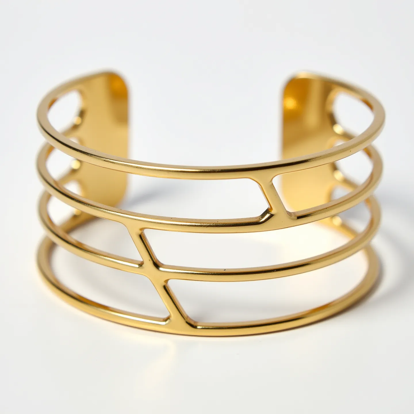 This gold cuff bracelet features a sleek and contemporary design crafted from polished gold. The cuff is characterized by its open framework, consisting of three horizontal bands connected by vertical segments that create a geometric pattern. The bracelet has an open-ended design, making it easy to slip on and off the wrist. The absence of any gemstones or additional embellishments highlights the minimalist elegance of the piece.