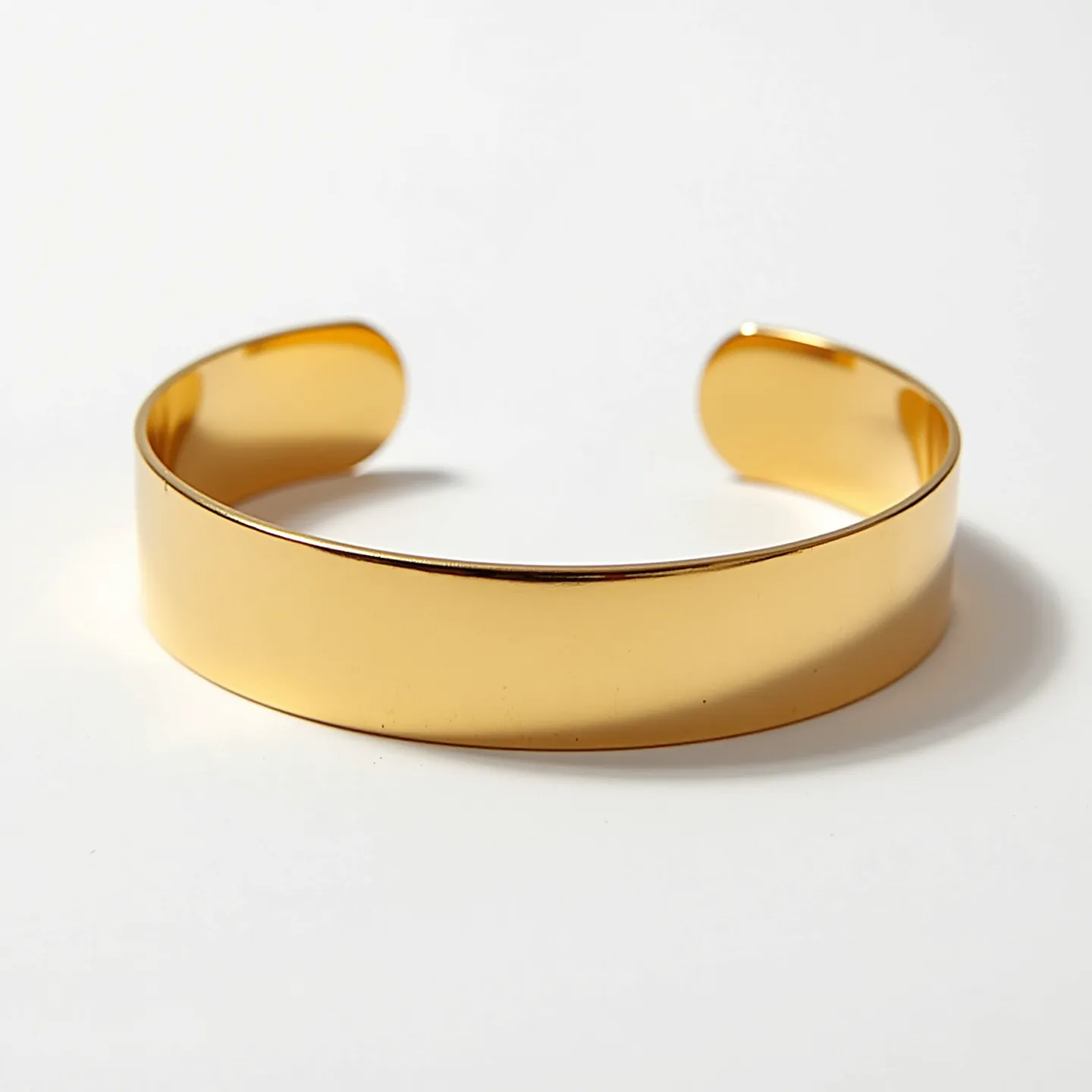 This gold cuff bracelet features a sleek and polished finish, made entirely of gold for an elegant and timeless appearance. The bracelet has a smooth, continuous surface and an open-ended design, allowing for easy wearing and a comfortable fit on the wrist. The surface of the cuff is free of any additional embellishments such as gems or stones, emphasizing the simplicity and sophistication of the piece. The absence of a clasp or other attachment highlights its minimalist style, making it a versatile accessory suitable for various occasions.