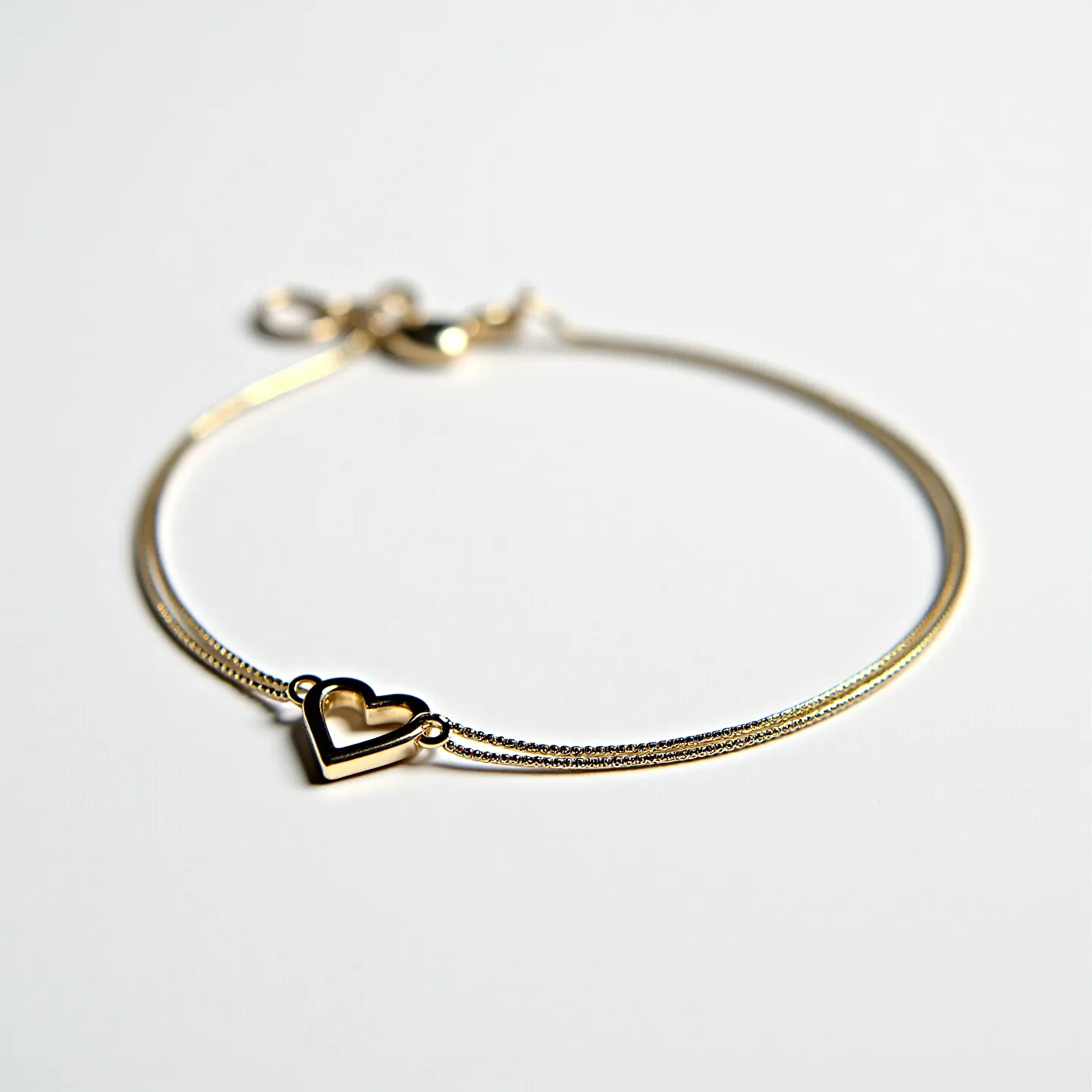 This heart bracelet features a delicate design, highlighted by a central heart-shaped charm that appears to be made of polished metal, likely gold or gold-plated. The bracelet band is composed of two fine, parallel chains that provide a refined and elegant aesthetic. These chains are connected to the heart charm on each side through small metal loops that attach securely to the charm's edges. The bracelet is equipped with a small lobster clasp, which ensures secure attachment and easy adjustment for the wearer. The overall design is simple yet sophisticated, making it perfect for everyday wear or special occasions.