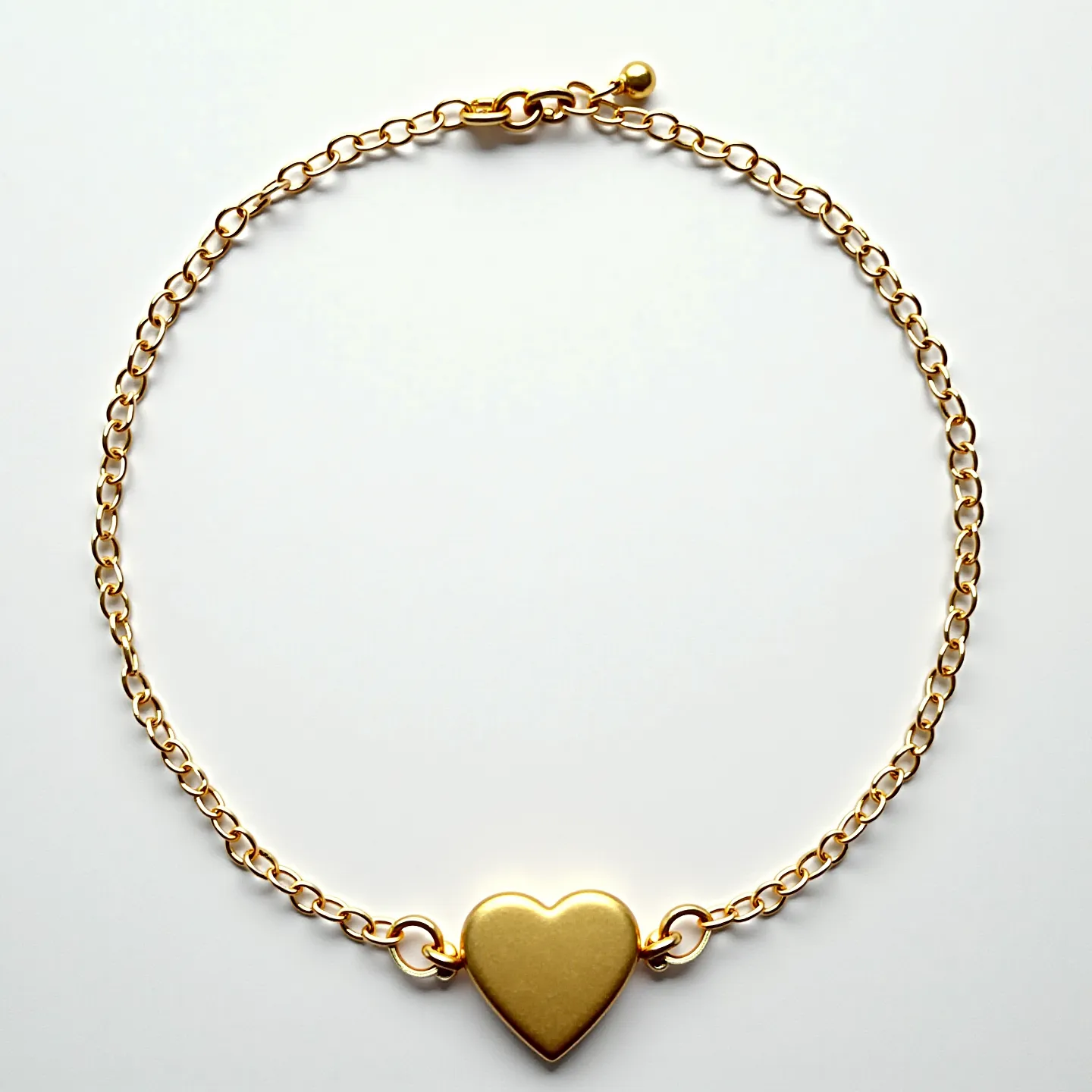 This heart bracelet features a delicate gold-toned chain that connects to a central heart-shaped pendant. The heart pendant appears to be made of a solid metallic material, matching the chain's gold tone. The chain links are uniformly sized and connected to the heart pendant by small, round jump rings on both sides. The bracelet is secured with a lobster clasp, complete with a small extension chain and a tiny ball at the end, facilitating easy adjustment for a comfortable fit. The overall design of the bracelet is simple yet elegant, with a minimalist aesthetic.