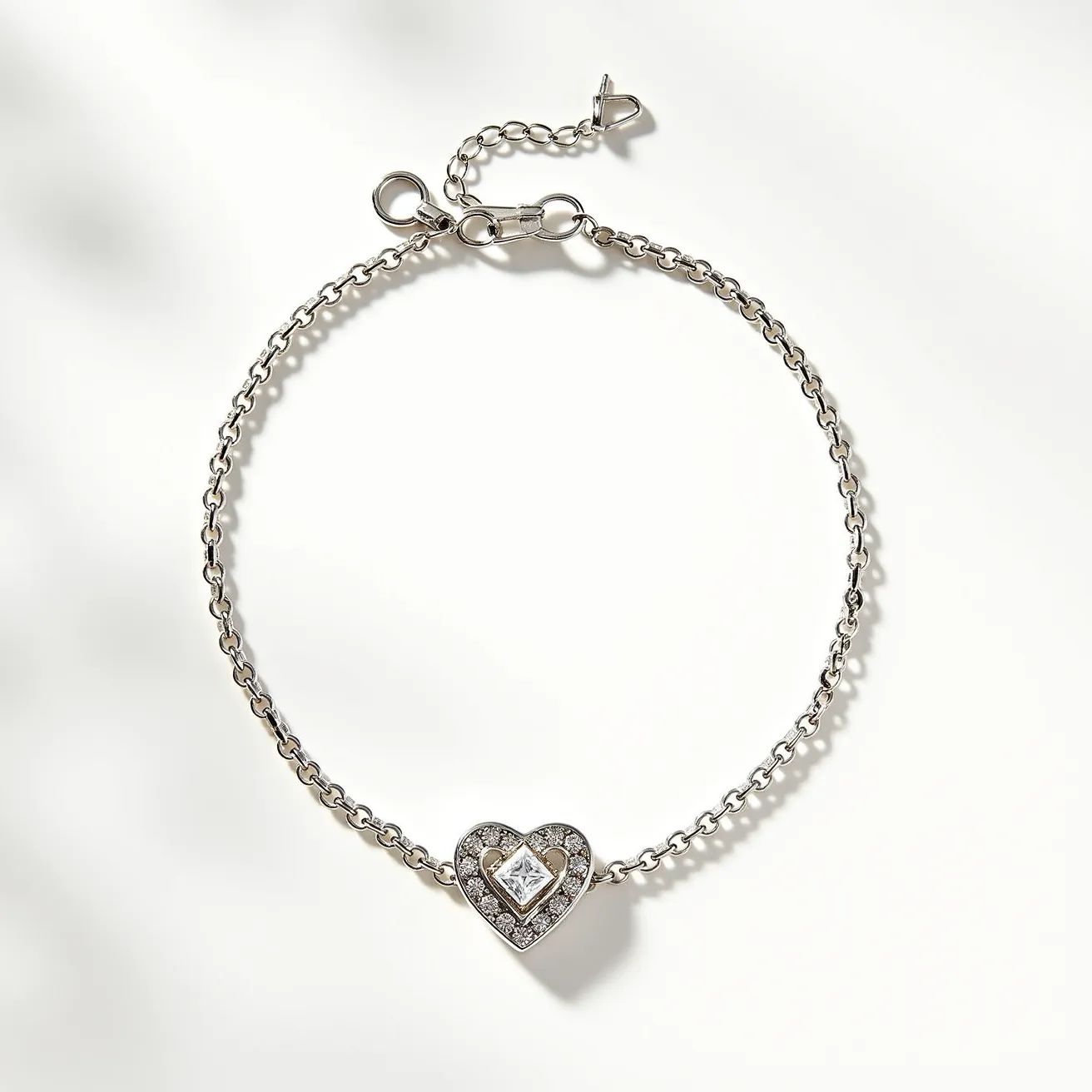 This heart bracelet features a delicate chain made of what appears to be silver or white gold, ensuring a sleek and elegant look. At its center lies a heart-shaped charm adorned with a central square-cut gemstone, likely a diamond, surrounded by smaller round-cut stones that enhance its sparkle. The setting of the stones appears to be prong-set, securely holding each gem in place while adding to the overall brilliance. The bracelet includes a standard lobster clasp and an additional adjustable chain, enabling a customizable fit for the wearer.