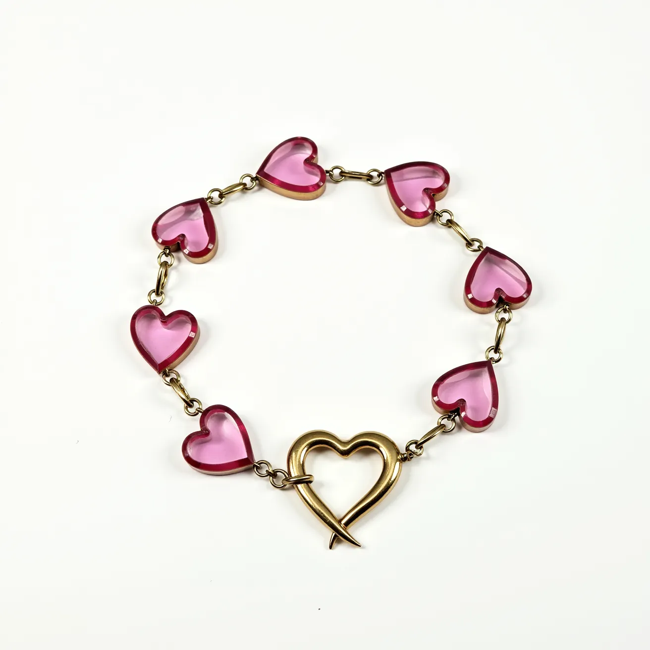 This heart bracelet features a series of pink heart-shaped gems, each connected by small chain links. The hearts appear to be made of a pink, translucent material, possibly glass or colored acrylic. They are smooth and polished, without any visible facets. Each heart is securely linked to the next via small, metallic jump rings that are likely made of a gold-toned metal. The bracelet closes with a heart-shaped clasp, which is also gold-toned and designed in a style that intertwines at the bottom for a secure closure. The overall design is simple yet elegant, with a cohesive and charming heart motif.