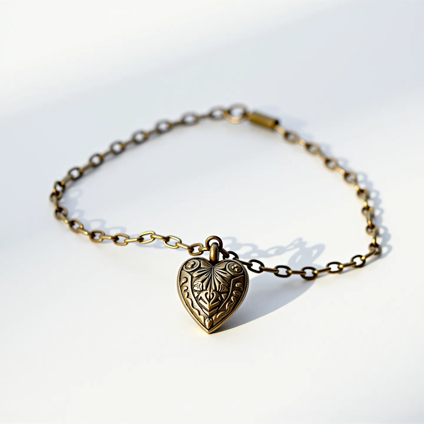 This locket bracelet features a delicate chain made of what appears to be a brass or bronze material, showcasing a warm, antiqued finish. The centerpiece of the bracelet is a heart-shaped locket adorned with intricate, embossed floral and leaf patterns that enhance its vintage charm. The locket is attached to the chain through a small loop, ensuring it hangs securely. The bracelet is fastened with a simple but functional lobster clasp, matching the chain’s metal finish and ensuring a secure closure. The craftsmanship and design of this bracelet suggest a piece that elegantly combines both utility and aesthetic appeal.