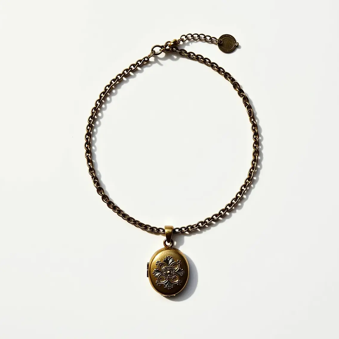 This locket bracelet features a brass chain with a vintage-style round locket pendant. The locket, which hangs from the center of the bracelet, is adorned with an intricate floral pattern, adding a touch of elegance and intricacy to the piece. It is secured by a lobster clasp, allowing for easy attachment and adjustment. The combination of the antique finish on the chain and locket gives the bracelet a classic, timeless appearance.