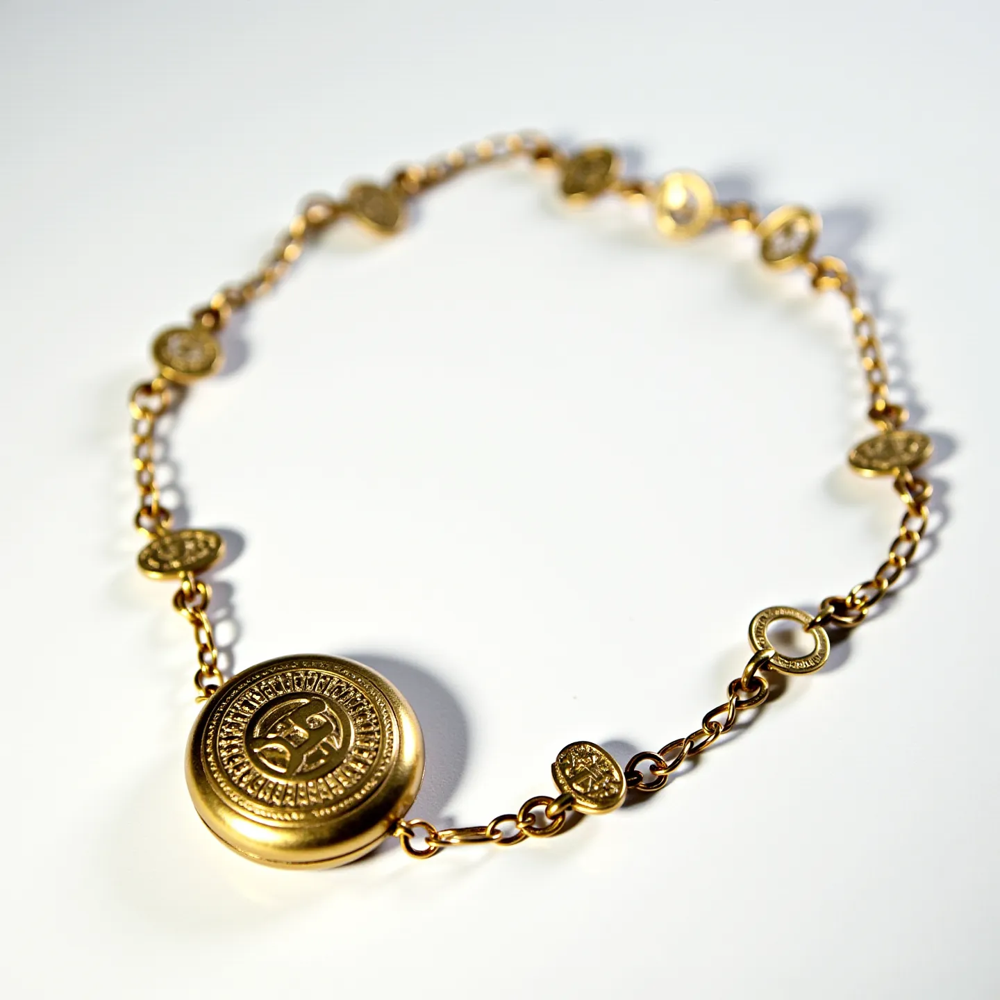 This locket bracelet features a central, circular locket that appears to be crafted from gold or gold-plated material. The locket is intricately designed with detailed engravings, giving it an antique or vintage look. The bracelet itself is composed of small, oval-shaped links interspersed with round, coin-like charms, also crafted from gold or gold-plated material. These charms have similar intricate designs, creating a cohesive aesthetic with the central locket. The bracelet connects with a delicate chain link and features a simple clasp for secure attachment, completing its elegant and timeless design.