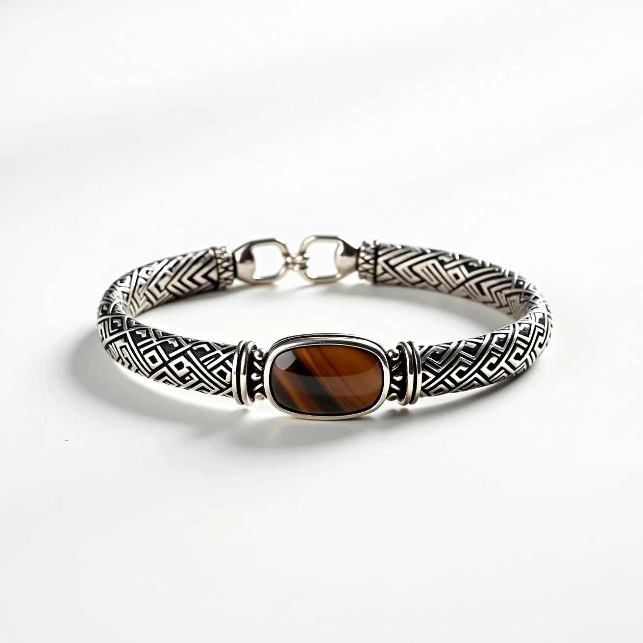 This men's bracelet features an intricate design with a bold central gemstone, likely a tiger's eye, which is oval-shaped and polished with a cabochon cut. The stone is set in a smooth, polished bezel, providing a sleek contrast to the detailed band. The bracelet itself is made of a durable metal, possibly silver, and showcases an elaborate geometric pattern throughout. The clasp is a sturdy hook-and-eye closure, ensuring both security and ease of wear. The combination of the earthy tone of the tiger's eye stone and the meticulous metalwork gives the bracelet a sophisticated and masculine aesthetic.