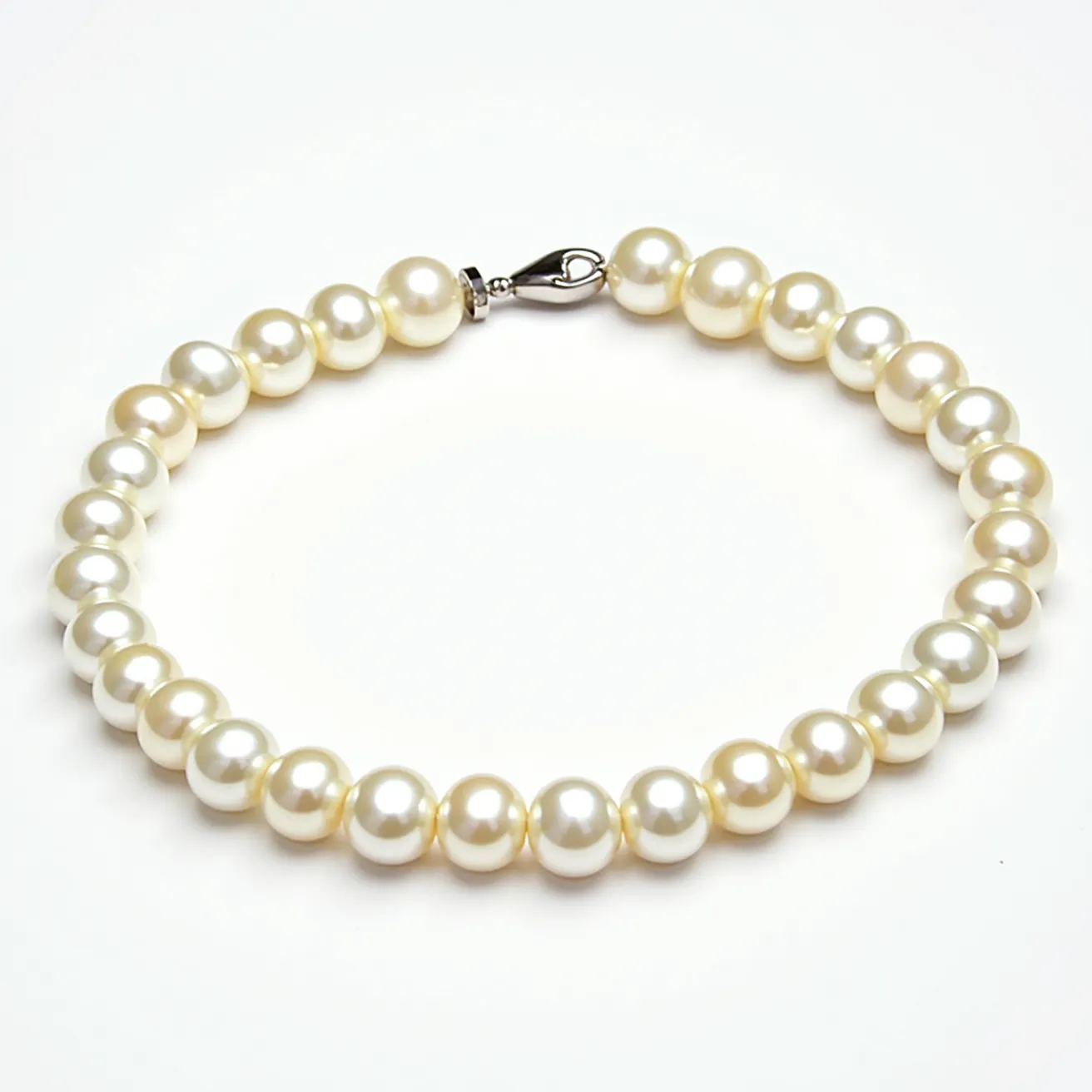 This pearl bracelet features a continuous string of lustrous white pearls, each uniformly round in shape. The pearls exhibit a high level of shine and smooth surface, indicating quality craftsmanship. The bracelet is secured with a metal lobster clasp, providing a reliable and easy-to-use closure. The pearls are carefully strung together on a likely durable thread or wire, ensuring both flexibility and strength in the bracelet design. The elegant simplicity of this piece makes it a versatile accessory suitable for various occasions.