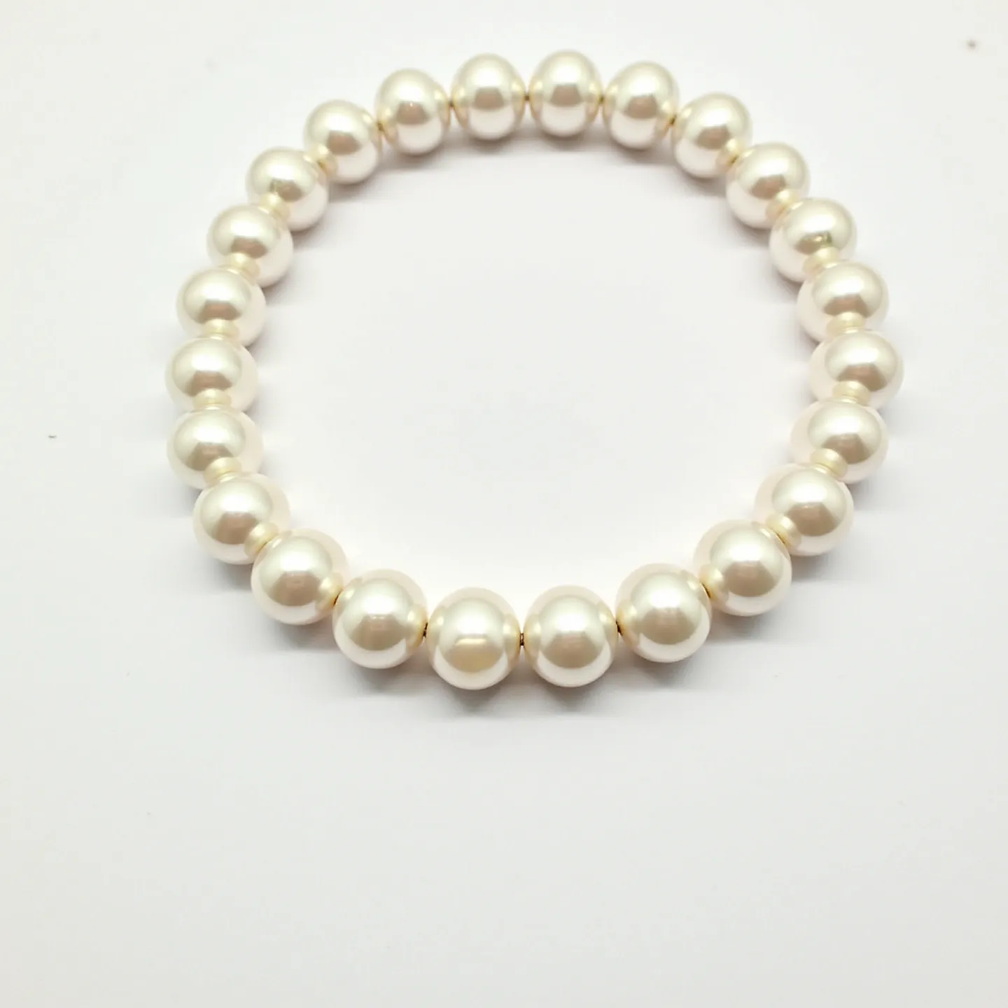 This pearl bracelet features a series of uniformly sized, lustrous white pearls strung seamlessly together. The pearls are of a smooth, classic round shape, creating an elegant and timeless design. The bracelet appears to be elastic, as there is no visible clasp or attachment mechanism, allowing for easy wearing and removal. The simplicity in its construction highlights the beauty of the pearls themselves, making it a versatile and sophisticated accessory.