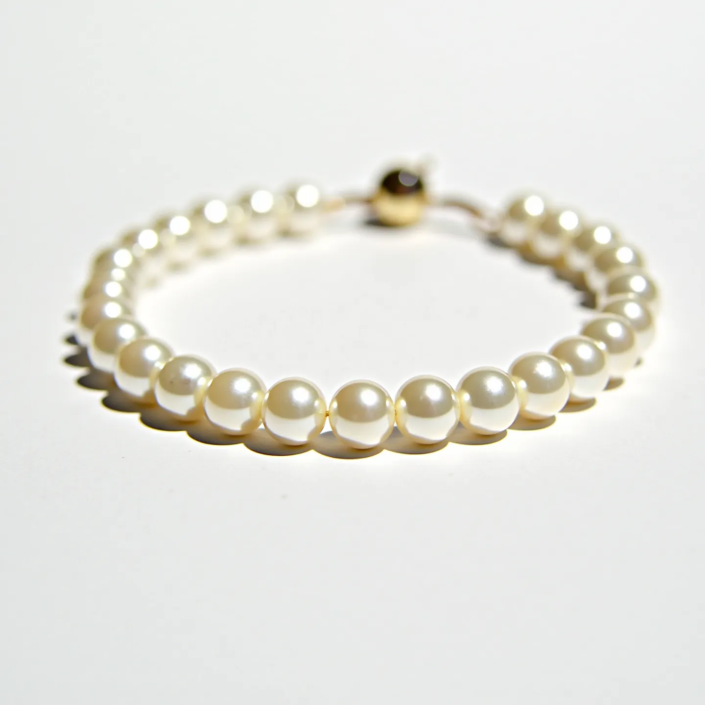 This pearl bracelet features a string of luminous, round pearls arranged in a single strand. The pearls display a classic lustrous sheen characteristic of high-quality pearl jewelry. They are uniform in size and shape, enhancing the elegance of the piece. The bracelet is secured with a spherical clasp that adds to its refined appearance. The simplicity and sophistication of the bracelet make it a timeless accessory suitable for various occasions.