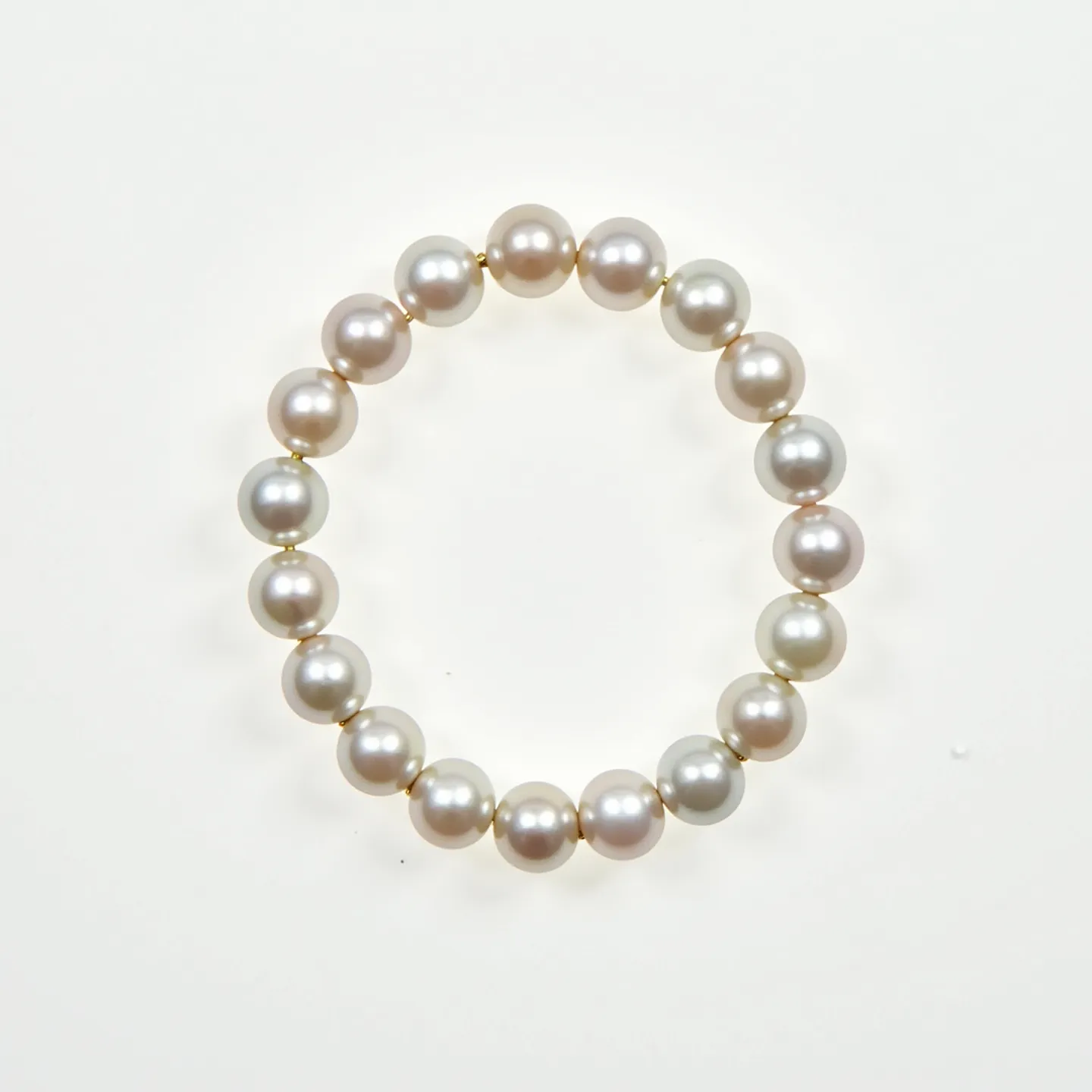 This pearl bracelet is composed of round, lustrous white pearls strung together in a continuous loop. Each pearl appears to be uniform in size, contributing to the overall elegance of the design. The pearls are interspersed with small, seemingly golden or metallic beads which both add a touch of contrast and serve to highlight the brilliance of each pearl. The absence of a visible clasp suggests that this bracelet might be elastic or stretchable, facilitating easy wear. The elegant and symmetrical arrangement of the pearls makes this bracelet a timeless piece of jewelry suitable for various occasions.