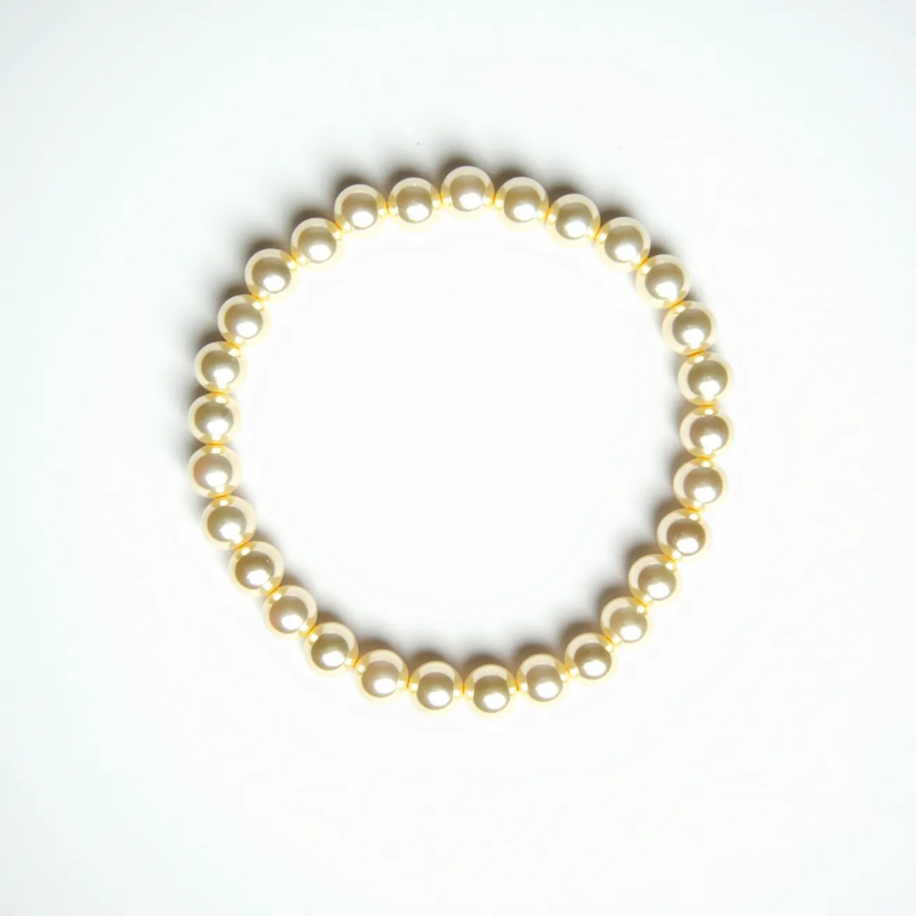 This pearl bracelet consists of a series of uniformly sized, round pearls displaying a smooth, lustrous surface. The pearls are arranged in a continuous loop, suggesting an elastic or stretchable design that negates the need for a clasp. Each pearl is meticulously knotted or strung on a flexible cord, ensuring durability and ease of wear. The bracelet does not feature any additional gemstones or elaborate settings, focusing solely on the elegance of the pearls themselves. The overall design exemplifies classic simplicity, combining timeless beauty with everyday functionality.