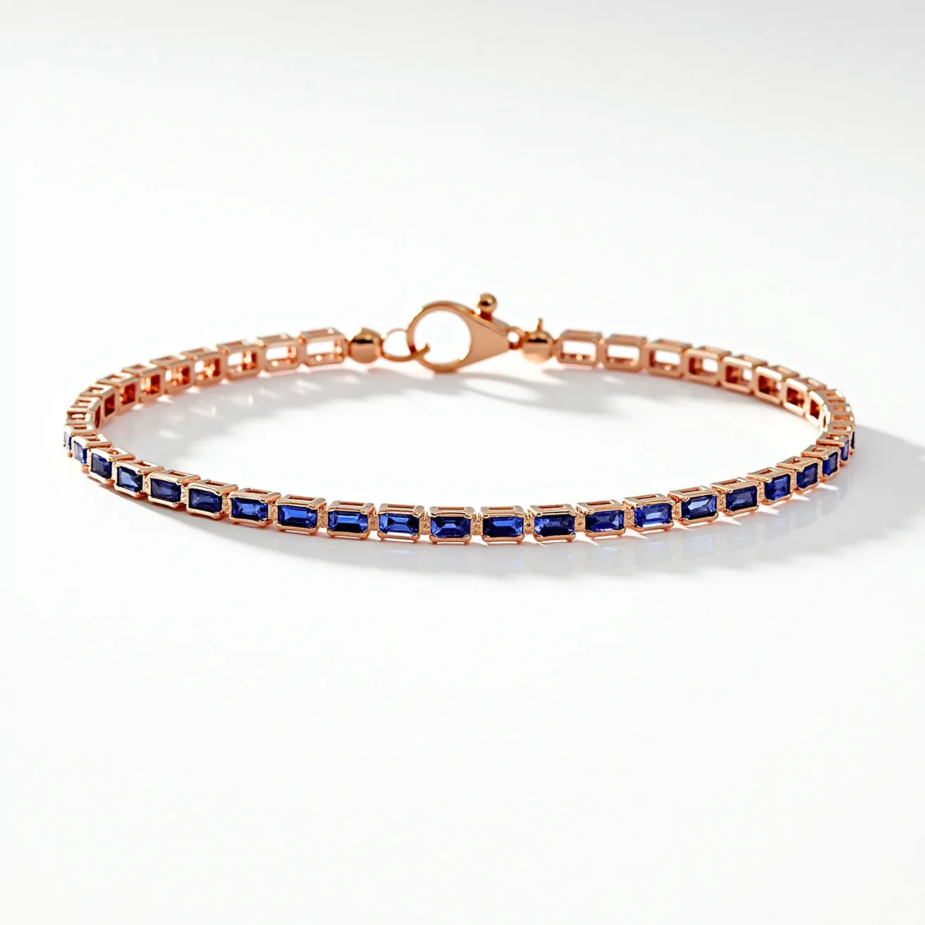 This tennis bracelet features luminous blue rectangular-cut stones set in a series of linked settings crafted from rose gold. Each stone is securely held in place, creating a continuous line of vibrant color and elegance around the wrist. The bracelet is fastened with a classic lobster clasp, ensuring a secure and comfortable fit while wearing.