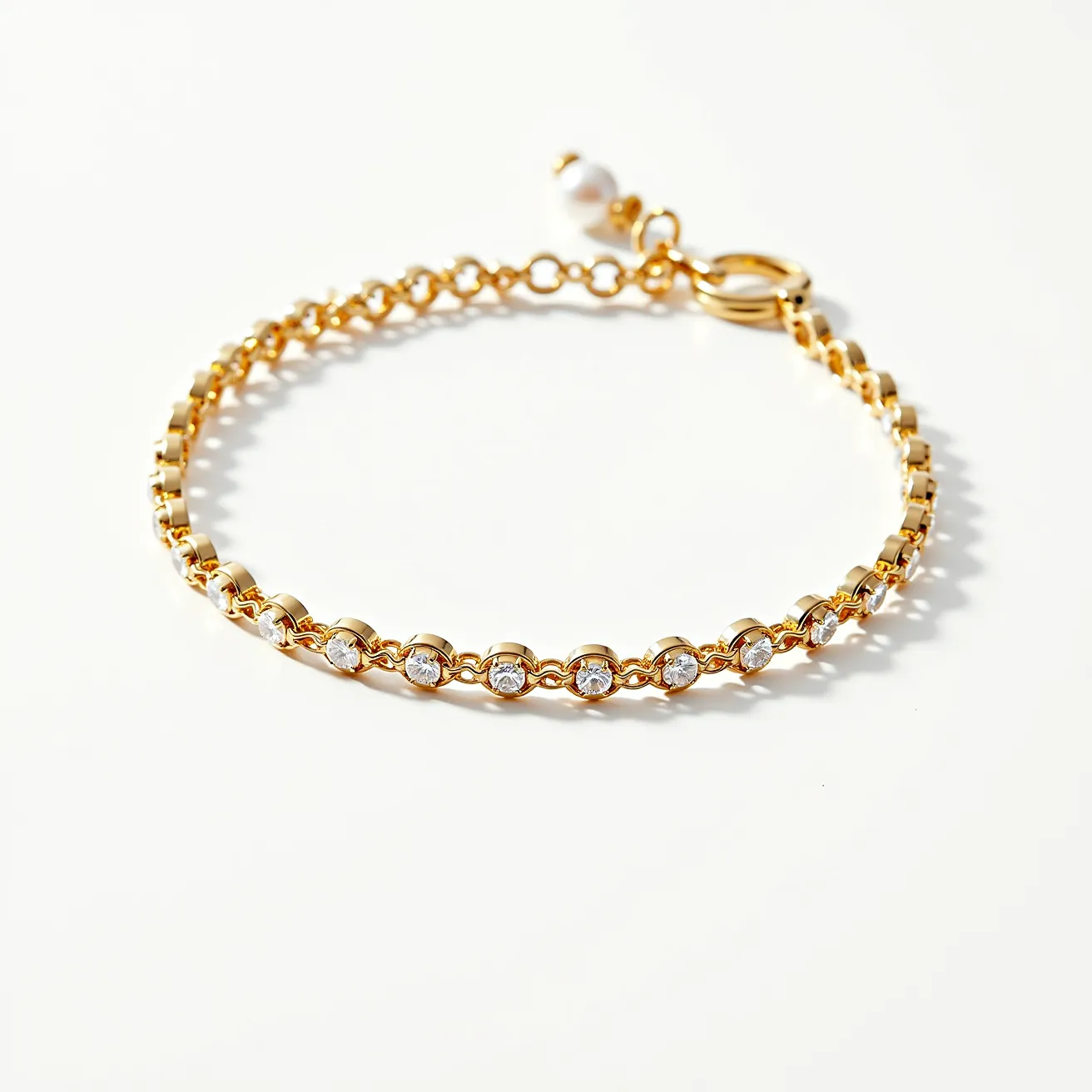 This tennis bracelet features a series of round-cut clear gemstones, each set within a yellow gold bezel setting that creates a seamless, elegant look. The gold chain links are finely crafted, ensuring both durability and flexibility for comfortable wear. The bracelet includes an adjustable clasp with a delicate extender chain finished with a small round bead, allowing for a customized fit. The combination of the shimmering gemstones and the warm tone of the gold gives this bracelet a luxurious and timeless appeal.