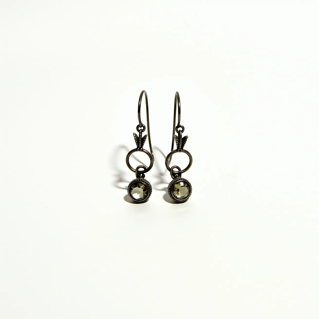 These 70s earrings feature a vintage design with a dark metallic finish, likely made from an aged metal such as brass or oxidized silver. They are adorned with round-cut gemstones of a subtle hue, suggesting the use of smoky quartz or similar stones, set in a bezel setting that enhances their reflective quality. The earrings are designed with a lever-back closure, providing a secure fit, and display a decorative element above the circular stone, adding to their retro charm and intricate craftsmanship.