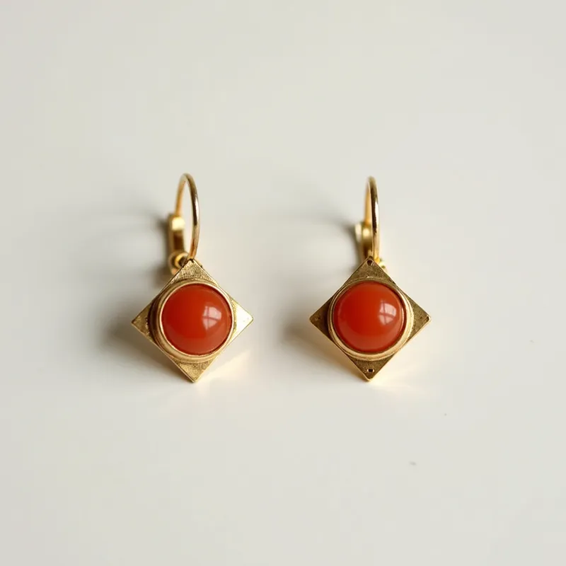 These 70s earrings feature a bold design with square gold-toned settings that hold round, polished stones in a rich orange hue, possibly carnelian. The stones are set in a simple bezel that allows their color to stand out prominently against the metal. The earrings attach with lever-back clasps, providing both security and comfort for the wearer. The geometric shape and vivid color of the stones make these earrings a quintessential example of 1970s fashion aesthetics, combining boldness with simplicity.