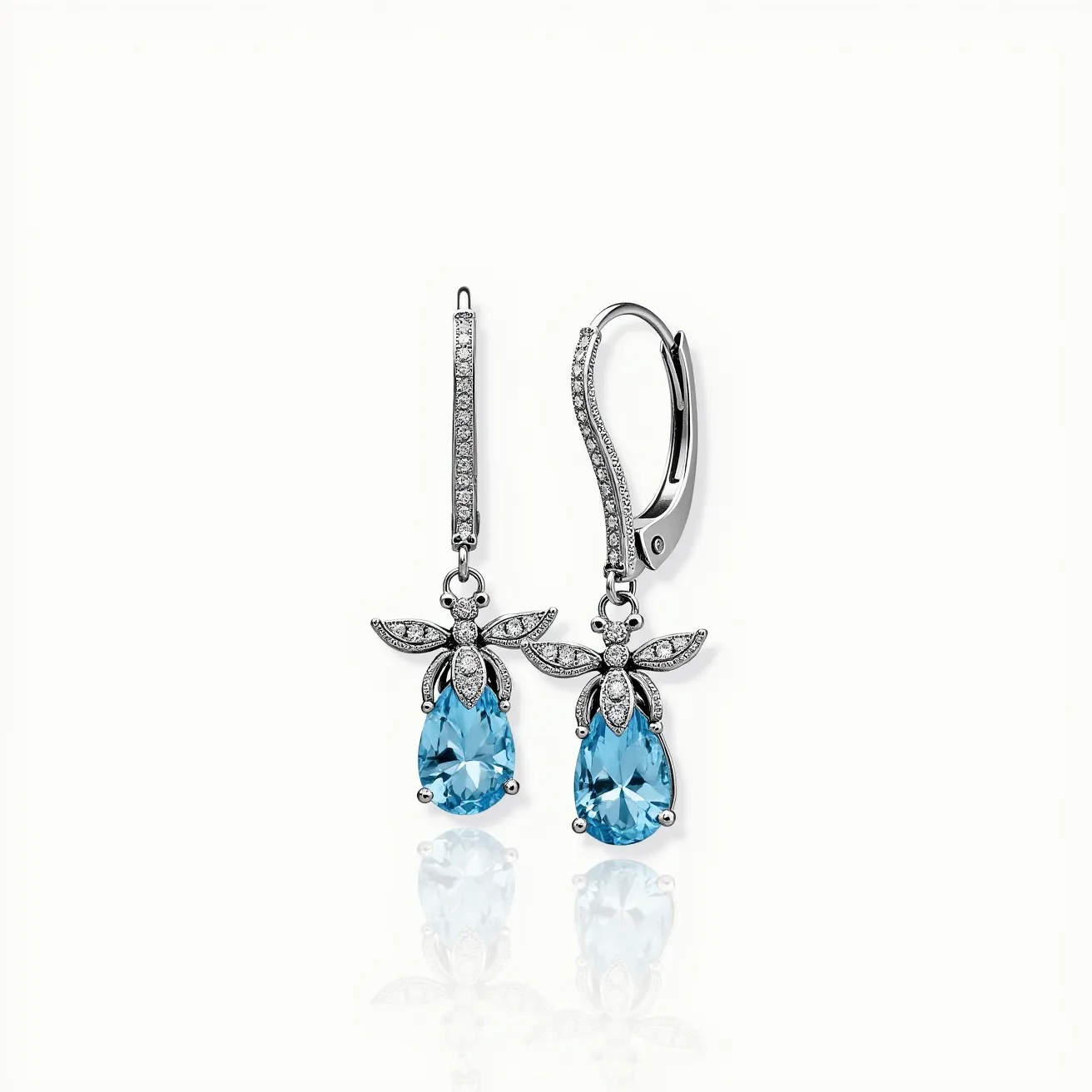 These bee earrings feature a delicate design with a metallic framework that outlines the form of a bee. The wings and body are adorned with clear, round-cut stones set in a pavé setting, adding a sparkling detail to the structure. The abdomen of the bee is represented by a larger, pear-shaped blue gemstone, securely set in a prong setting. The earrings are suspended from a lever-back clasp, ensuring a secure and comfortable fit. The combination of the glimmering stones and the vibrant blue gem creates an elegant and eye-catching accessory.