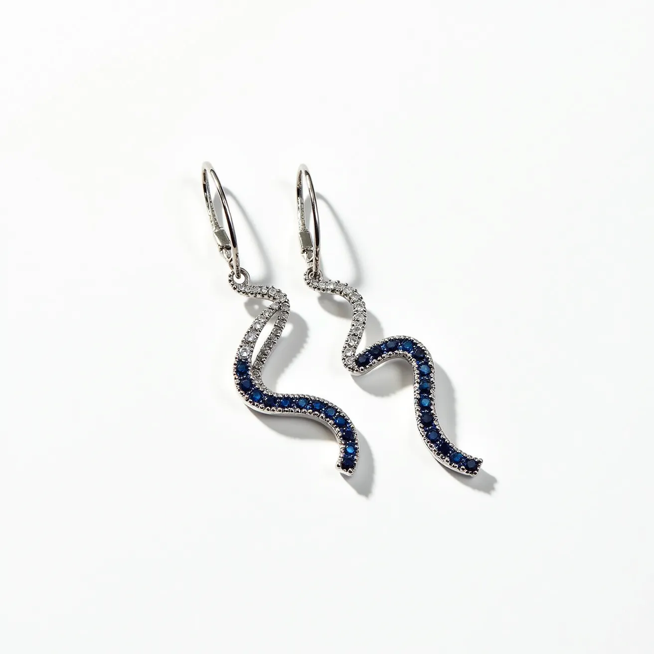 These birthstone earrings feature a sleek and elegant design with a wavy structure, adorned with small, round-cut blue gemstones that likely represent sapphire, a common birthstone for September. The stones are set in a pave-style setting that enhances their sparkle and allows them to catch the light beautifully. The earrings are crafted from a silver-toned metal, possibly silver or white gold, adding to their sophistication and complementing the deep blue of the stones. They are secured with a lever-back clasp, providing a secure and comfortable fit for the wearer.