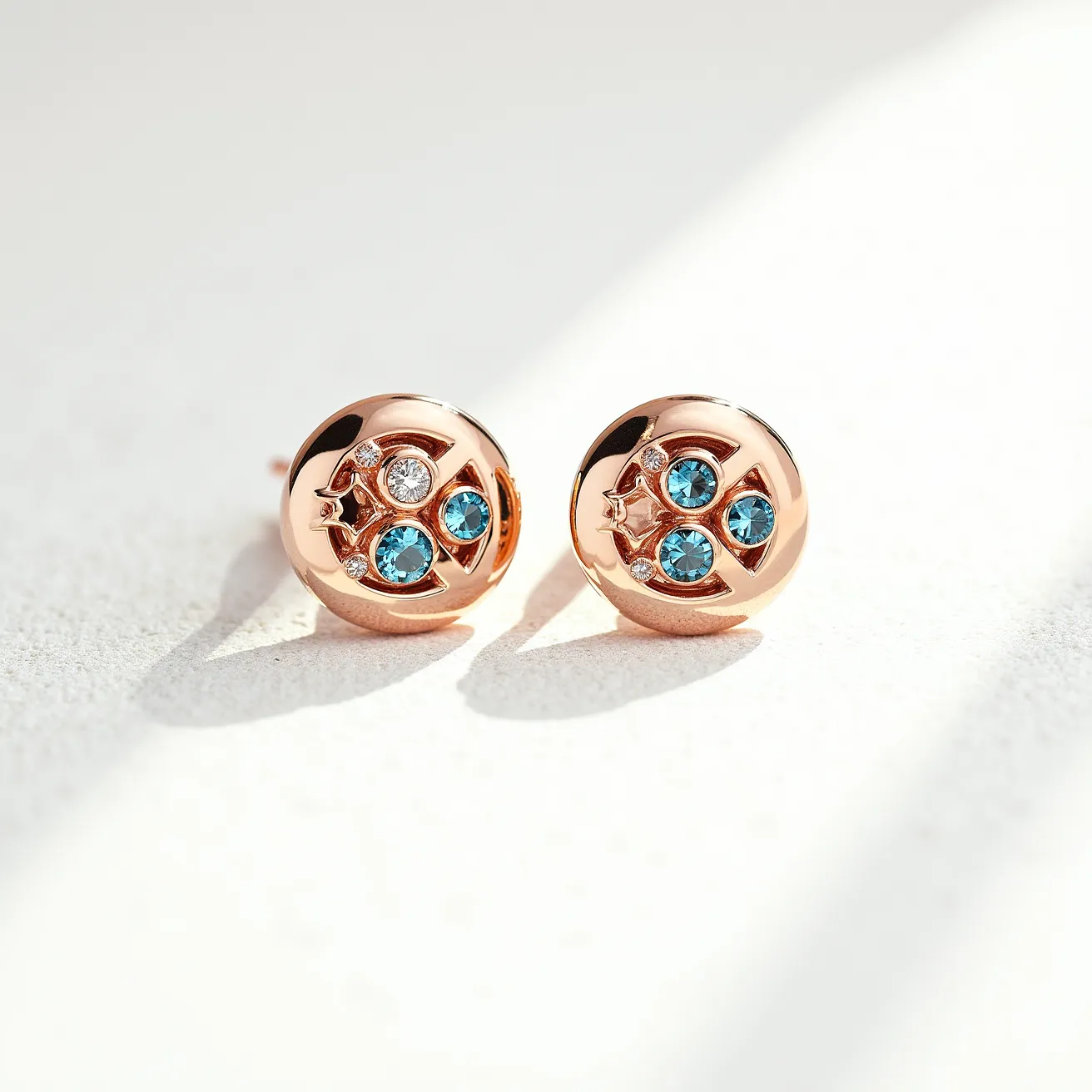 These birthstone earrings feature a round, rose gold setting that accentuates the central design. Each earring displays three round-cut blue gemstones, possibly topaz or aquamarine, elegantly arranged in a triangular pattern. Complementing these birthstones are small, shimmering white stones, likely diamonds, set within the same piece, adding a touch of brilliance. The earrings have a simple stud attachment, ensuring they are both secure and comfortable to wear.