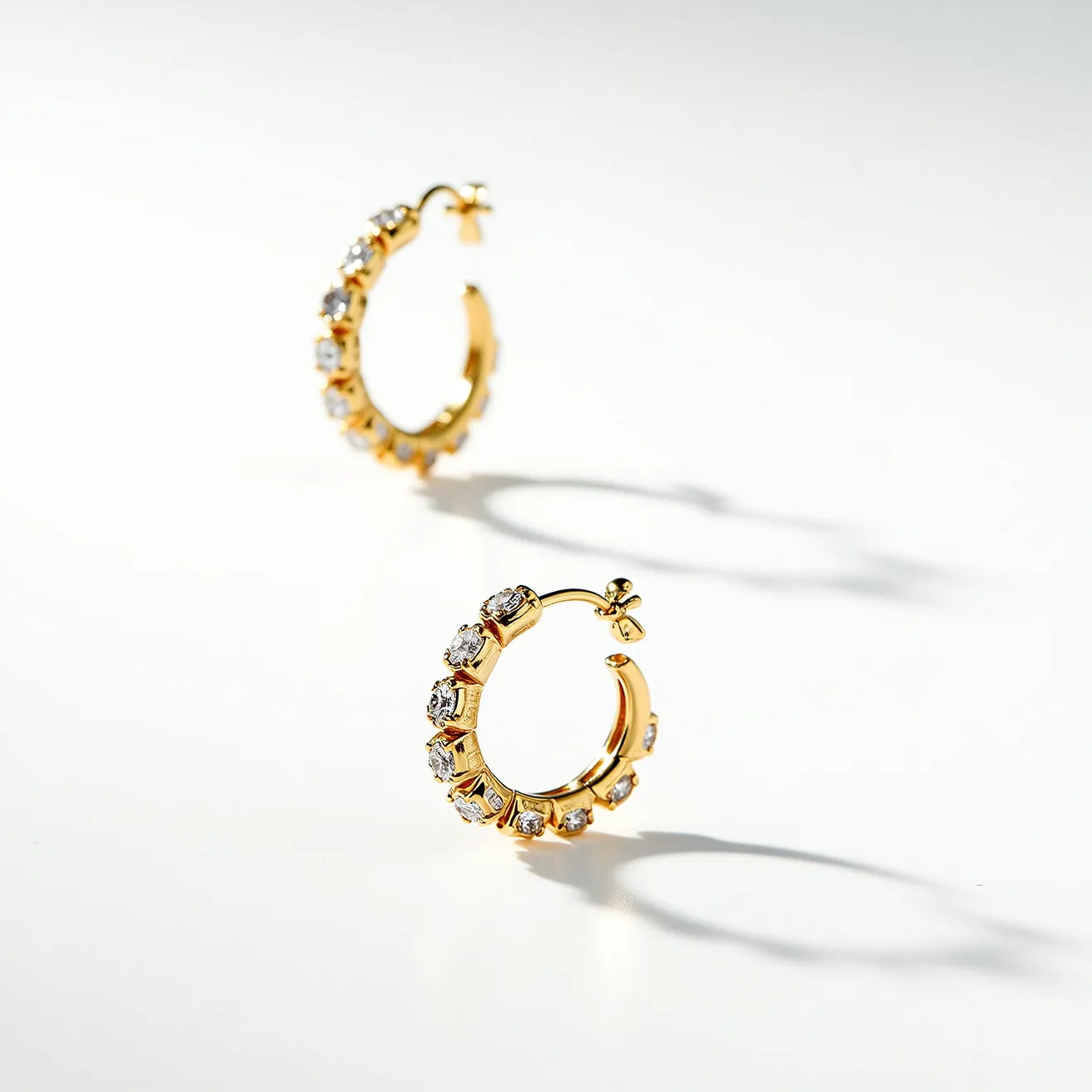 These cartilage hoop earrings feature a sturdy gold-toned metal base, elegantly encrusted with a series of sparkling round-cut gems, possibly diamonds or cubic zirconia, positioned in a secure prong setting along the entire surface of the hoop. Each gem appears to be uniformly cut, enhancing their reflective brilliance and the overall luxurious appearance. The hoops are designed with a hinge clasp that provides a secure and comfortable fit, allowing ease of wear for cartilage piercings. The meticulous craftsmanship and choice of materials evoke a timeless elegance and sophistication.