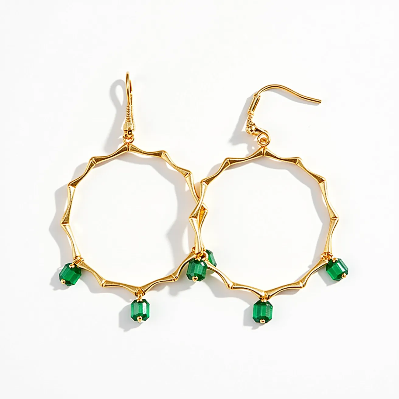 These circle earrings feature a gold-toned metal structure with a zigzag pattern forming the circular design. Attached to the bottom of the circle are three green faceted beads, likely made from glass or a similar material, each hanging from a small gold-toned loop. The earrings are fitted with a fishhook clasp, allowing for easy attachment to pierced ears. The combination of the vibrant green beads with the gold-toned metal creates an eye-catching and stylish look.