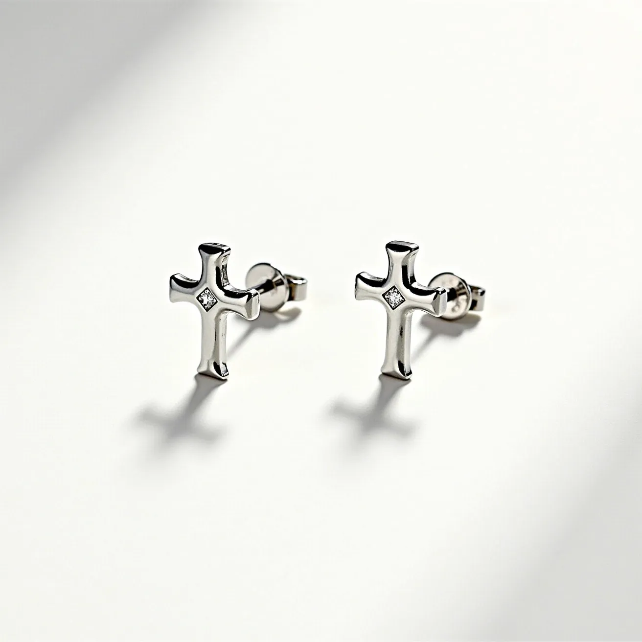 These cross earrings for men are designed in a timeless, elegant style featuring a polished metallic finish, likely silver or stainless steel. The centerpiece of each earring is a small, round gem, possibly a diamond or cubic zirconia, set in a prong or bezel setting at the intersection of the cross shape. The earrings are equipped with a post and butterfly clutch back, ensuring a secure fit when worn. The minimalist design highlights the subtle sparkle of the gem, making these earrings versatile for both casual and formal occasions.