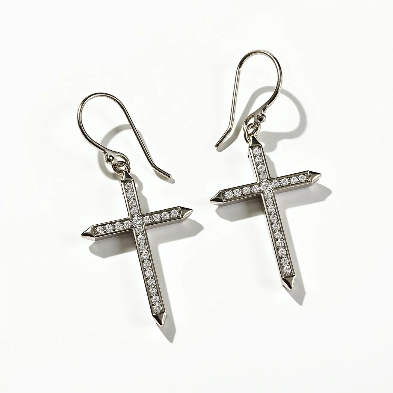 These cross earrings for women feature a sleek, metallic design made from what appears to be a polished silver or white gold material, giving them a refined and elegant look. Each arm of the cross is adorned with a series of small, sparkling gems, likely diamonds or high-quality cubic zirconias, set in a row to enhance their brilliance. The stones are round in shape, adding a subtle texture against the metal backdrop, set within a secure channel setting that highlights their shimmer. The earrings are designed with a simple and classic hook clasp, providing an effortless and secure attachment for comfortable wear.