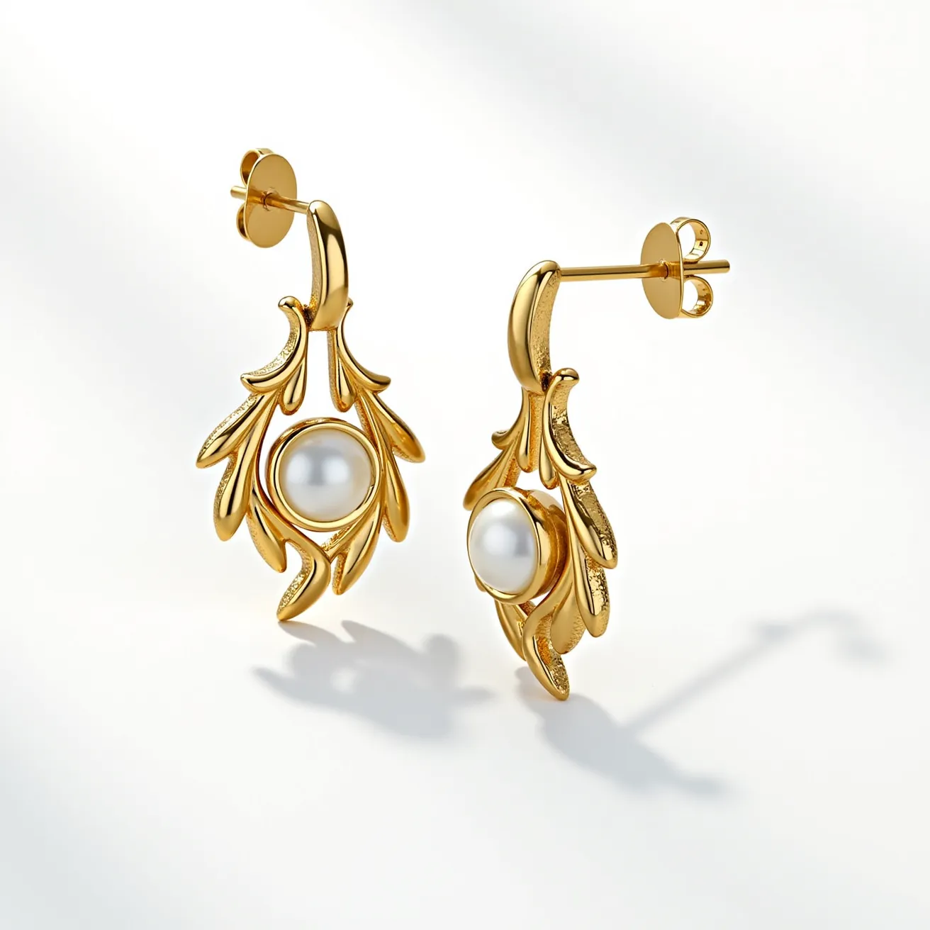 These dangle earrings feature an elegant design crafted from a gold-toned metal, with intricate leaf-like motifs extending downwards. At the center of each earring sits a round, lustrous pearl, prominently displayed and securely set within the design. The earrings attach with a butterfly back clasp, ensuring a secure and comfortable fit when worn. The combination of the rich gold hue and the smooth, glossy pearls creates a sophisticated and classic aesthetic, suitable for various occasions.