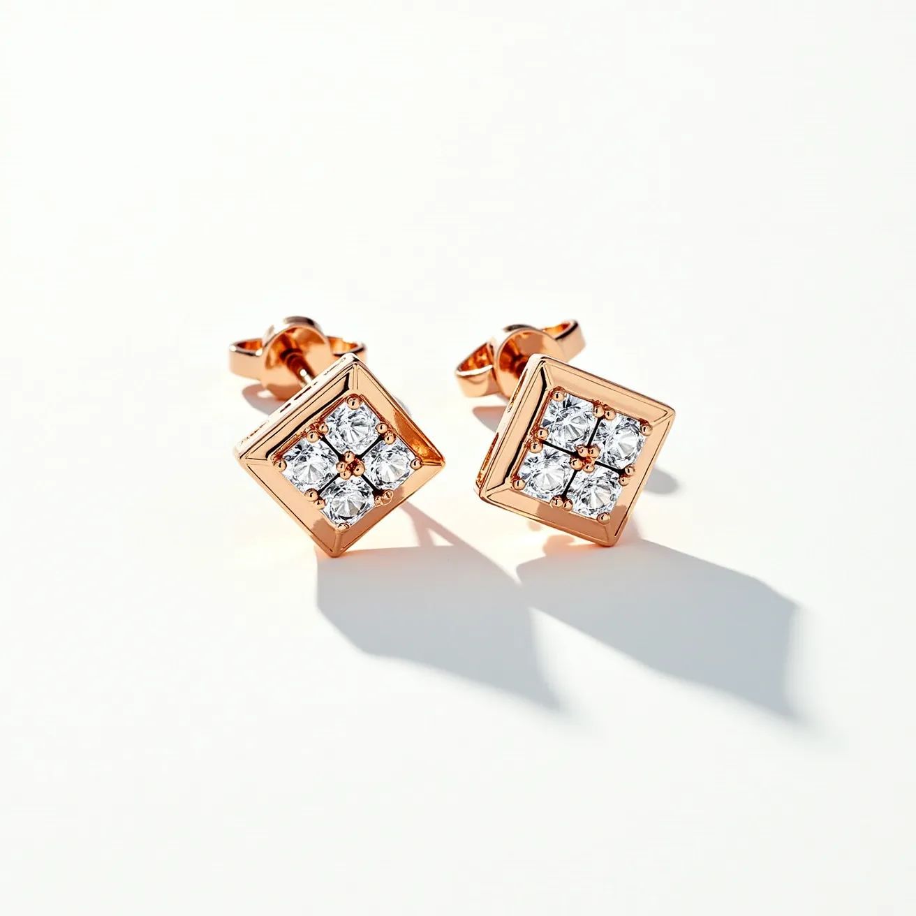 These diamond earrings feature a striking combination of materials and design elements. Each earring showcases a cluster of four round-cut diamonds set in a square formation, creating a dazzling focal point. The diamonds are securely held in place with a prong setting, enhancing their brilliance and sparkle. The setting and overall structure of the earrings are crafted from rose gold, which adds a warm, elegant contrast to the shimmering diamonds. These earrings are attached with a butterfly clasp, providing a secure and comfortable fit.