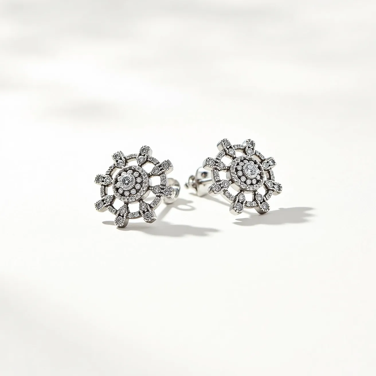 These diamond earrings are crafted with an intricate floral design, showcasing a brilliant arrangement of round-cut diamonds. Each earring features a central cluster of smaller diamonds forming a captivating core, surrounded by a network of larger diamonds set in a radiating pattern that resembles petals. The metal appears to be white gold or platinum, providing a sleek and elegant backdrop that enhances the sparkle of the gems. The earrings are secured with a traditional post and butterfly clasp, ensuring a secure and comfortable fit. This exquisite combination of materials and design highlights the luxurious nature of these statement earrings, making them a stunning addition to any jewelry collection.