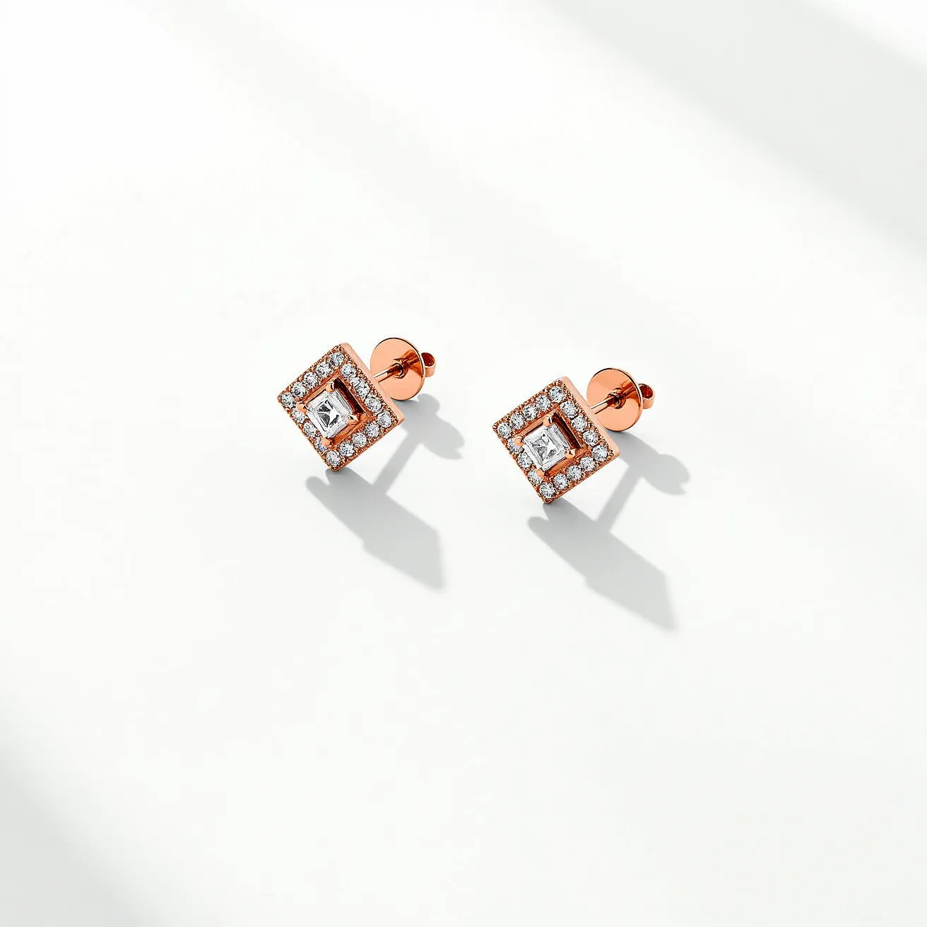 These diamond earrings feature a central square-cut diamond set in a geometric design. Each earring showcases a square setting with a rose gold finish, accentuated by a halo of smaller round diamonds that enhance the central stone's brilliance. The earrings employ a push-back clasp, ensuring secure and comfortable wear. The combination of the square and round-cut diamonds, along with the warm rose gold setting, creates an elegant and modern aesthetic.