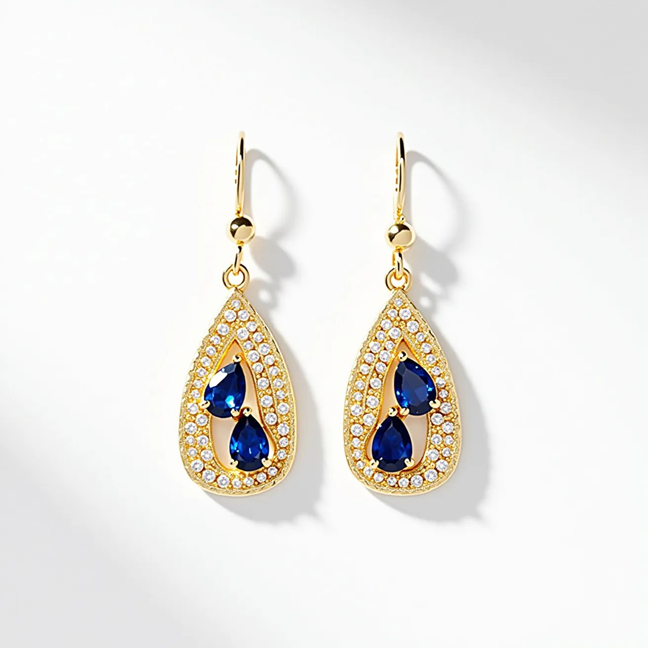 These drop earrings feature a beautifully crafted design with a gold-toned metal forming the teardrop shape. At the center of each earring are two deep blue, pear-shaped gemstones, likely sapphires, which are elegantly set in a prong setting. Surrounding these vibrant stones is a stunning array of small white gems, possibly diamonds or cubic zirconia, in a pavé setting that enhances the overall sparkle of the earrings. The earrings attach with simple and elegant hooks, ensuring ease of wear while maintaining their luxurious appearance.